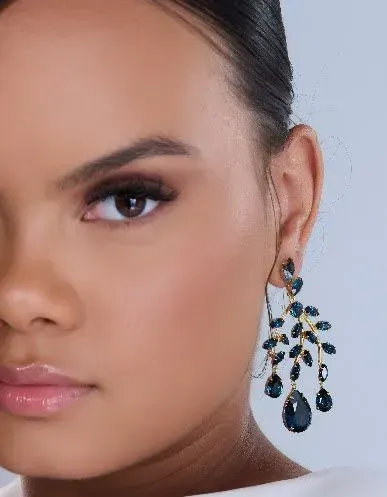 Woman wearing elegant dark blue jeweled chandelier earrings.