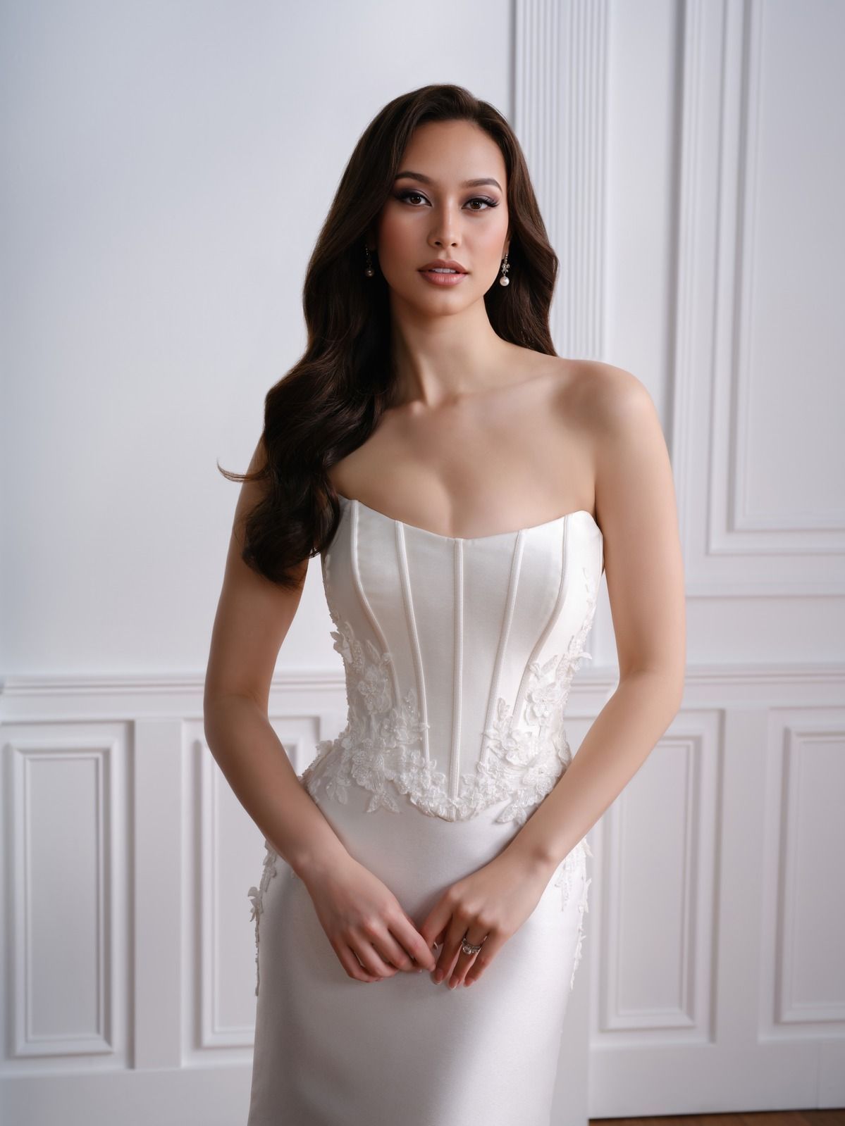 Woman in a white strapless gown standing in a bright room with paneled walls and wood floors