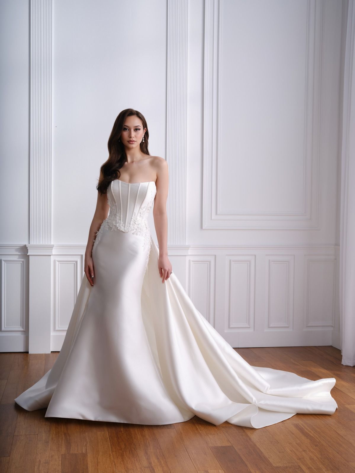 Woman in a white strapless wedding gown standing in a bright white paneled room