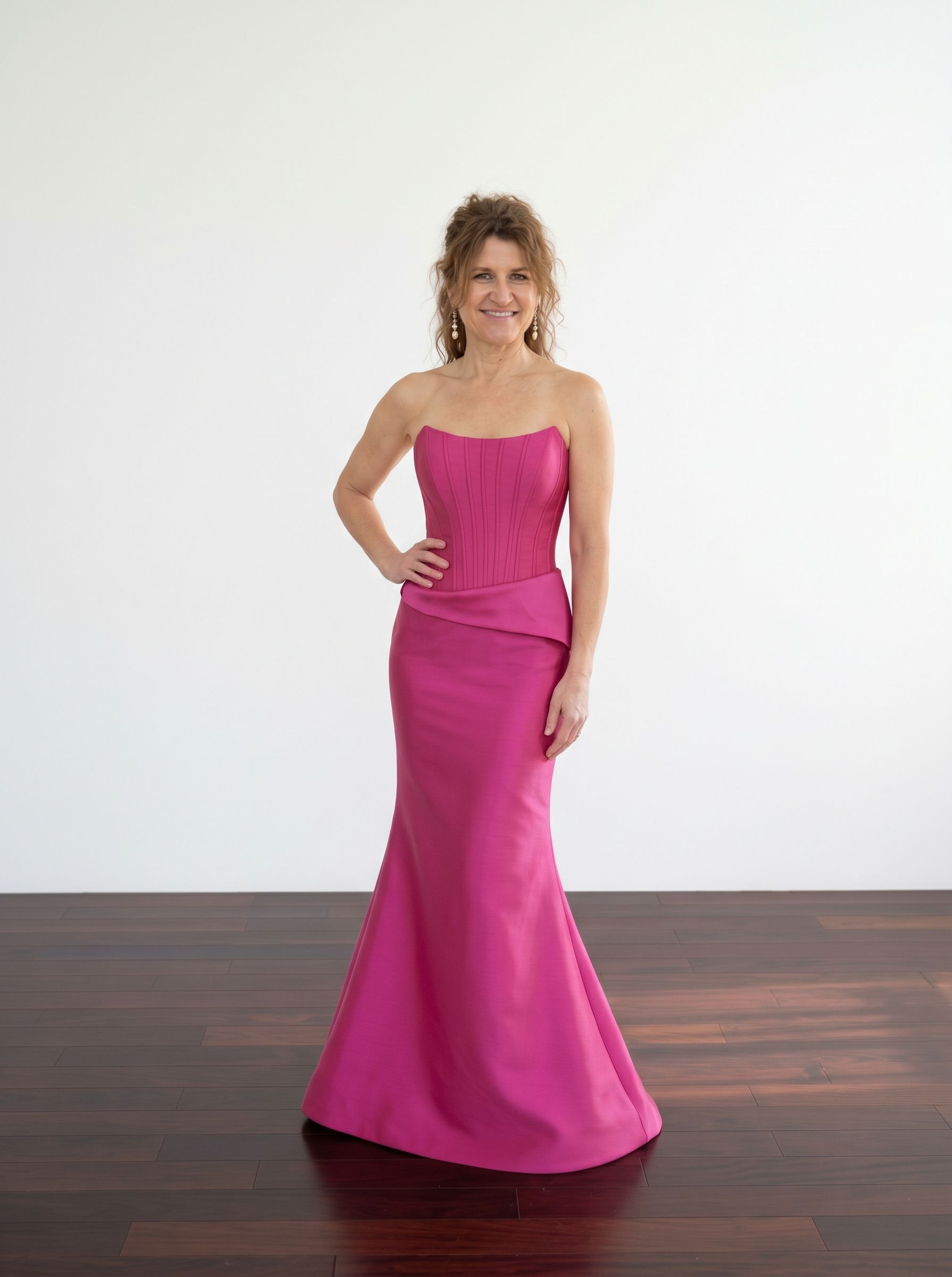 Woman in a dark brown strapless gown standing in a white paneled room.