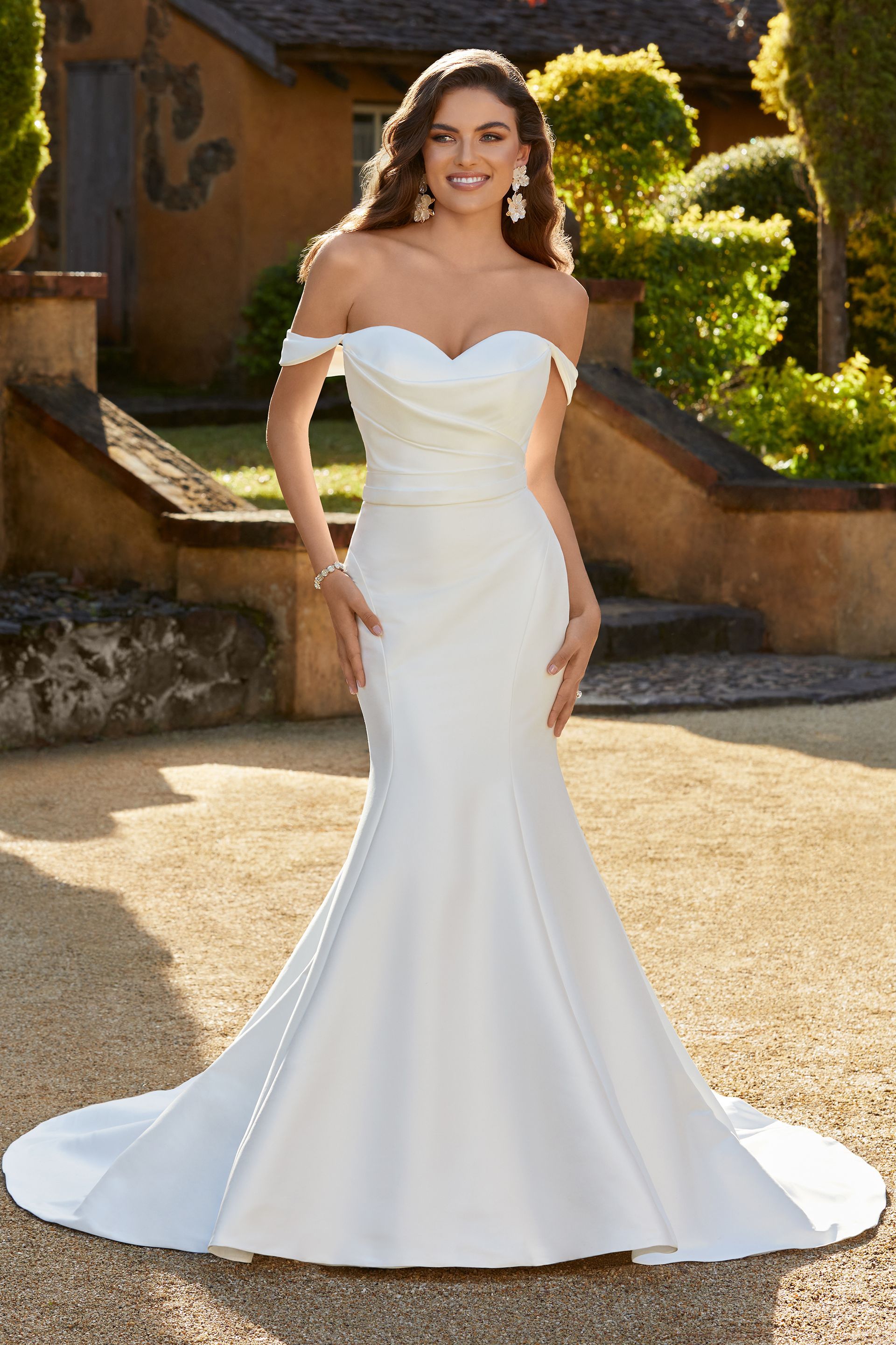Woman in a white strapless wedding dress standing outdoors in a garden setting