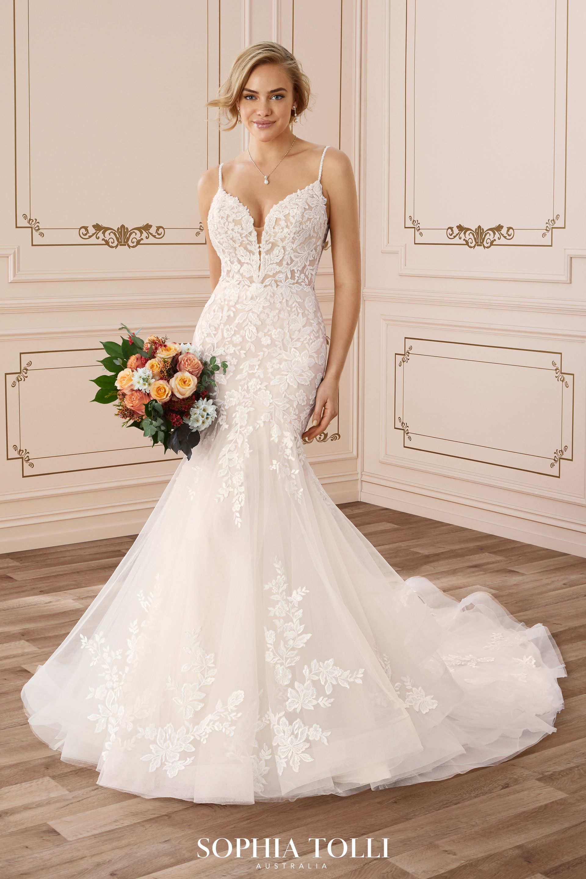 Woman in a white lace mermaid wedding dress, veil, and jewelry outdoors.