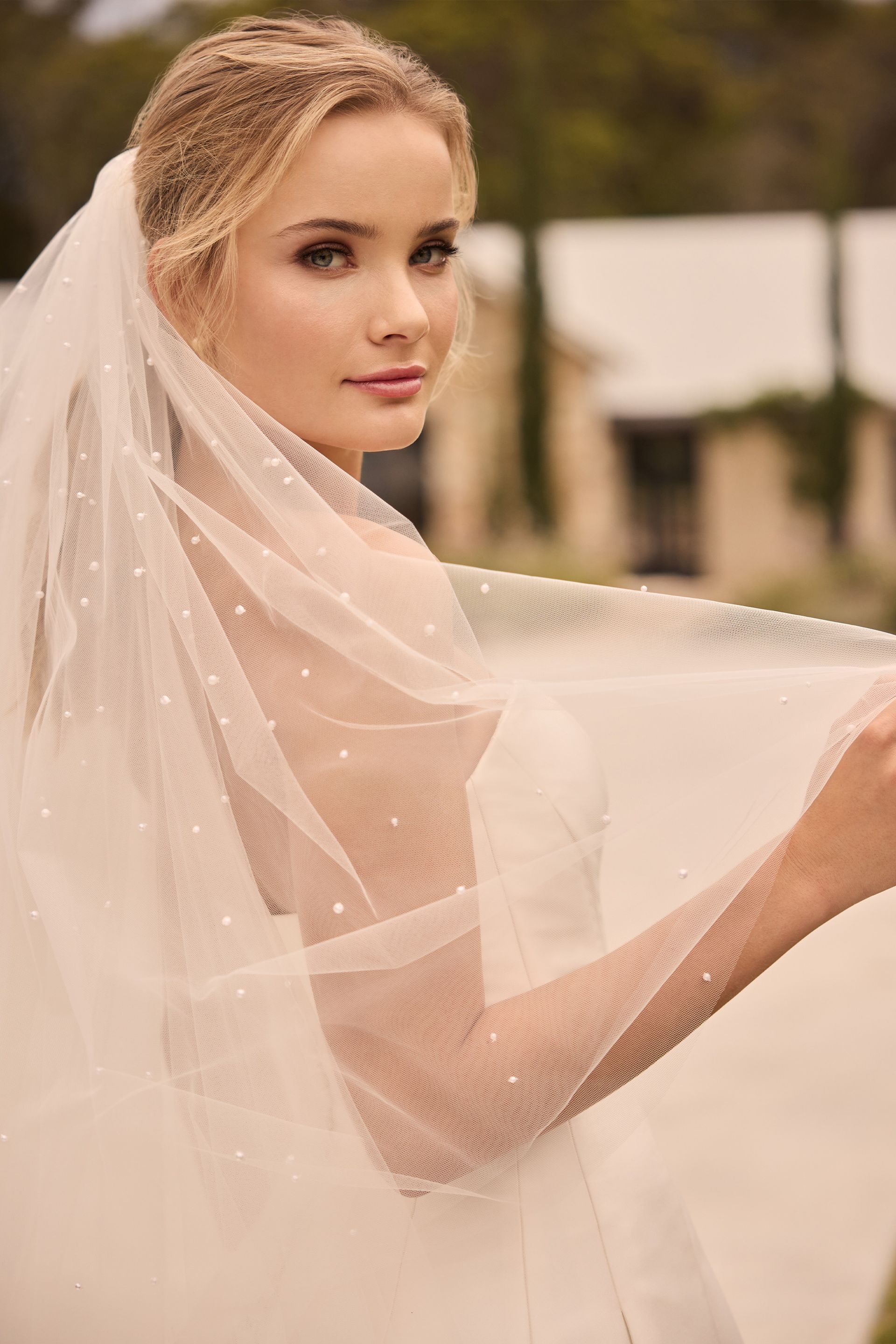 Woman in a white wedding dress and veil, looking over her shoulder. Woman in a white wedding dress and veil, looking over her shoulder.