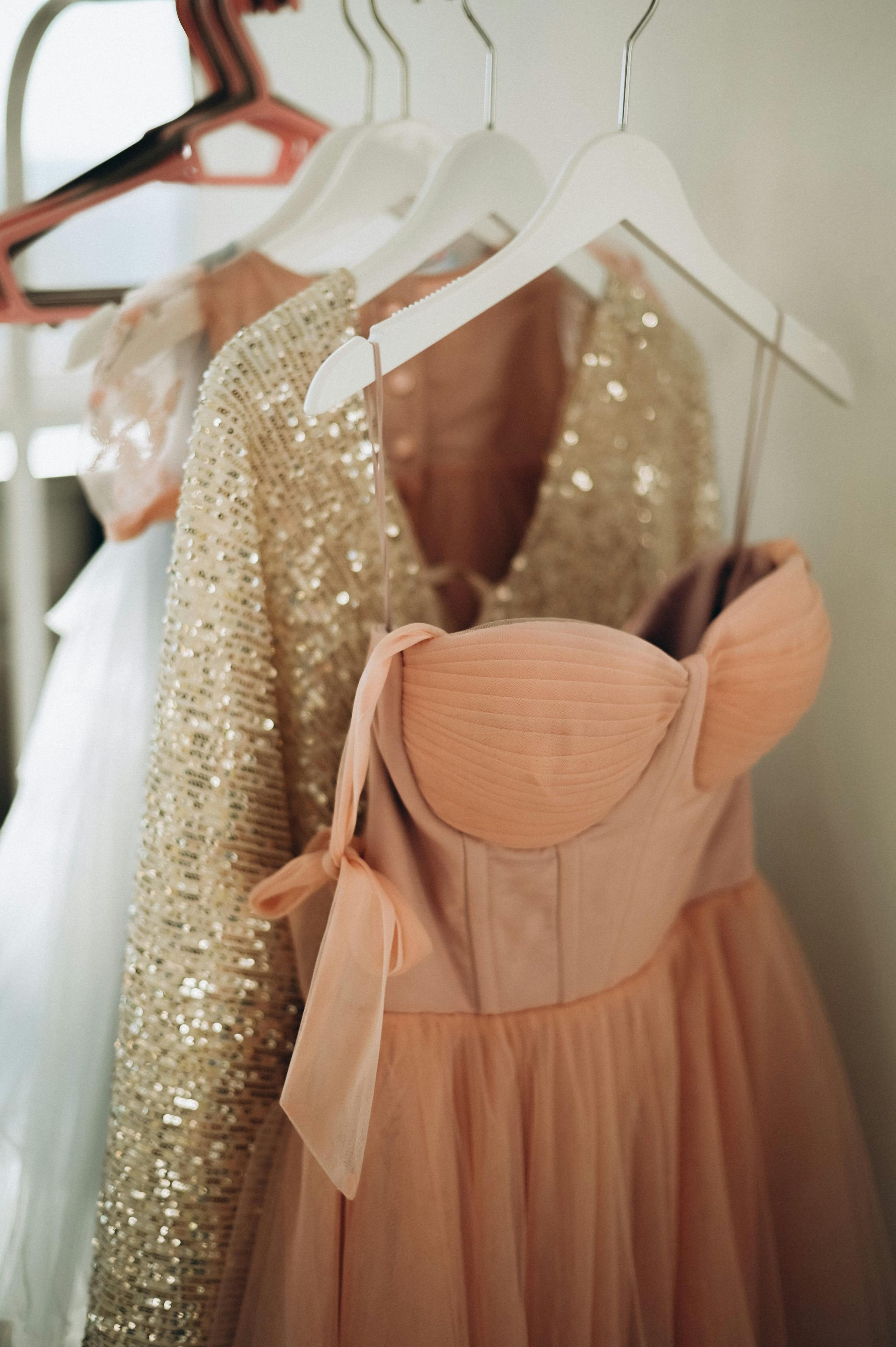 Dresses hanging on a rack; a sequined top and a strapless pink dress are visible.