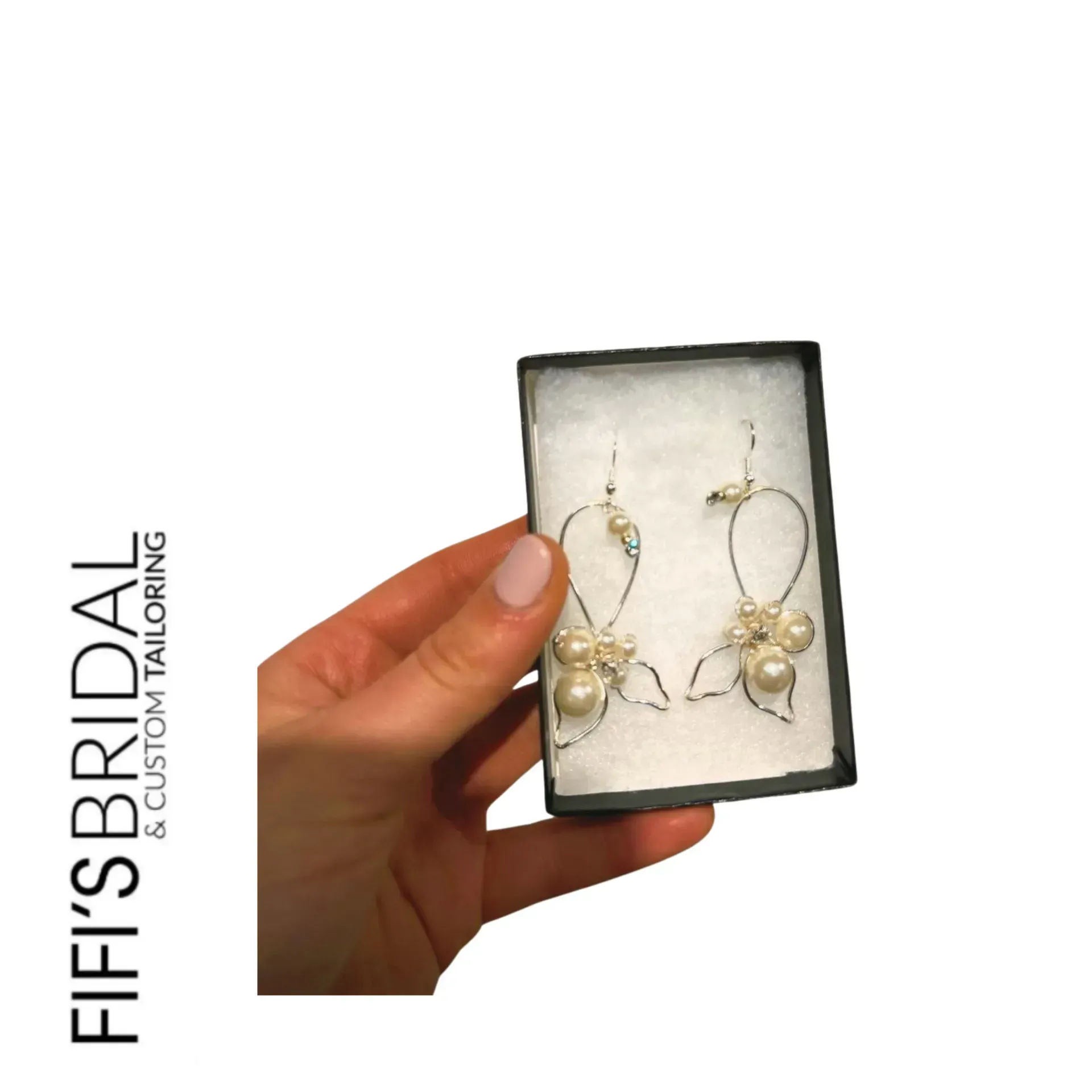 Gold-toned chandelier earrings with clear, faceted gemstones on a burlap jewelry stand against a wood background.