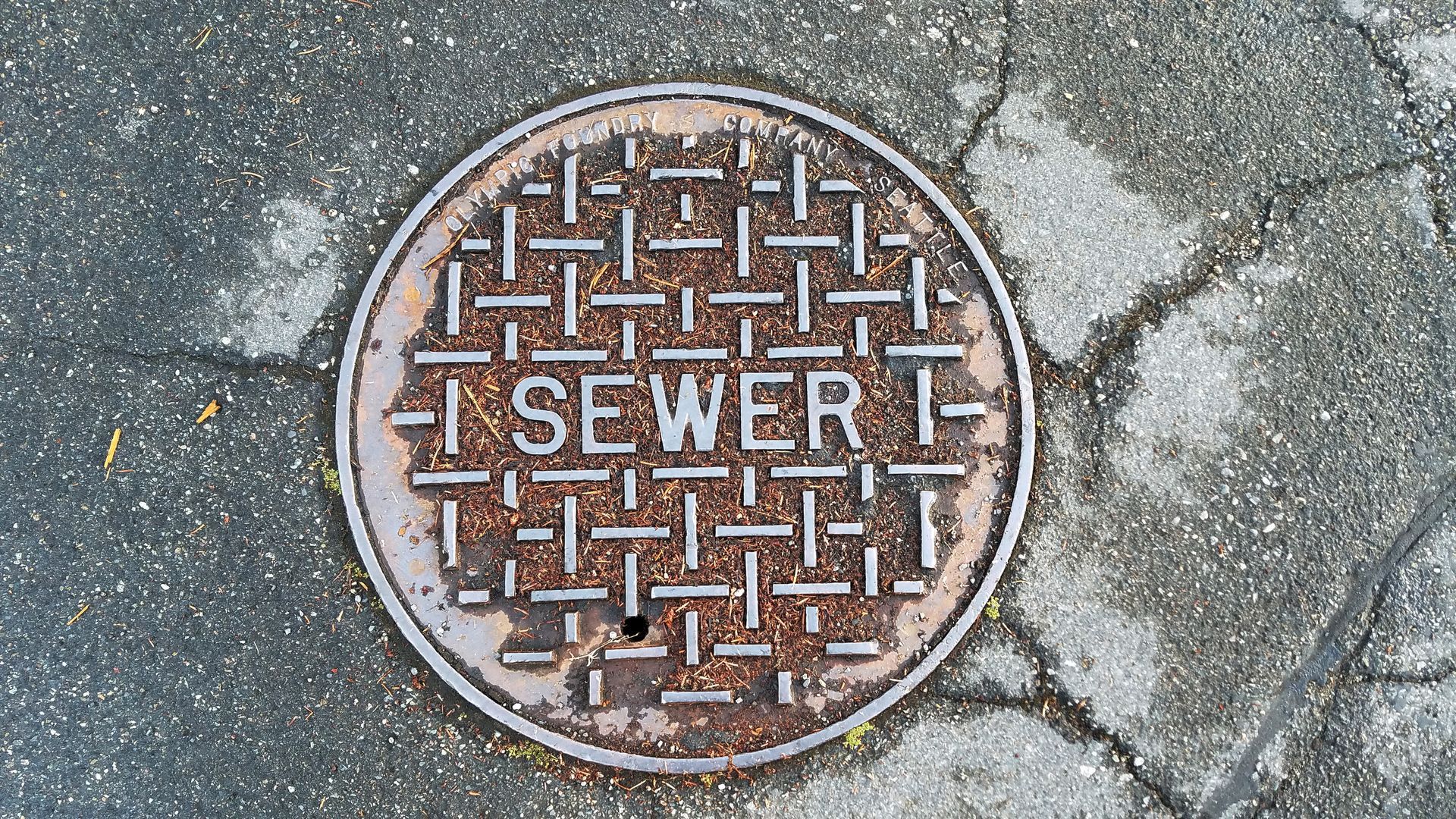 Construction worker installing a manhole cover on a utility access opening.