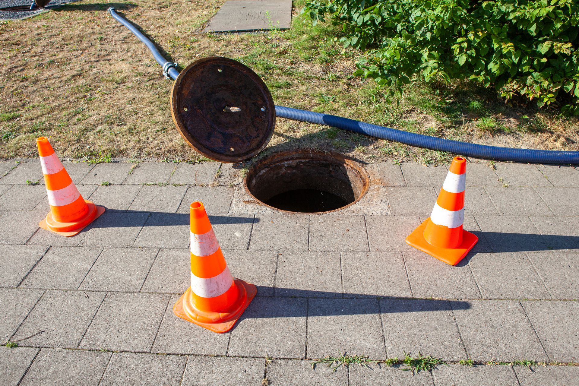 Open manhole with cones on sidewalk. Open manhole with cones on sidewalk.