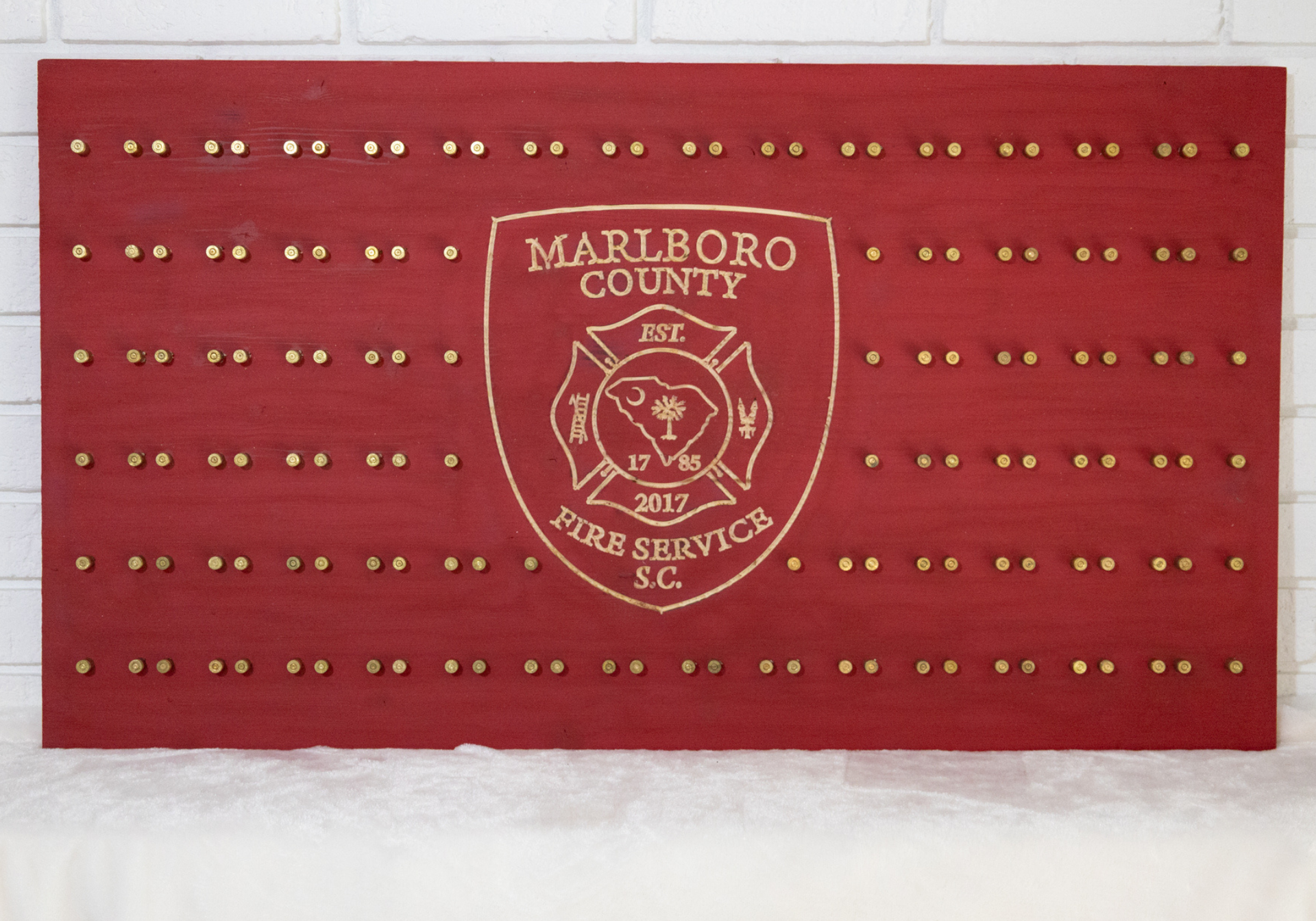 Red wooden display board with brass studs, Marlboro County Fire Service logo.