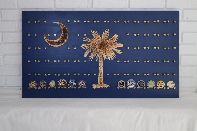 South Carolina flag art on a blue board with gold star studs and coins at the bottom.