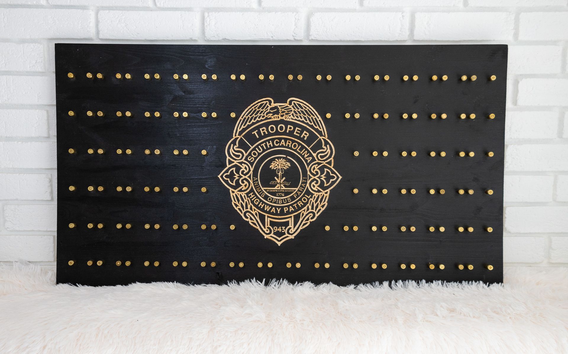 Black wooden board with a gold police badge and gold pin studs.