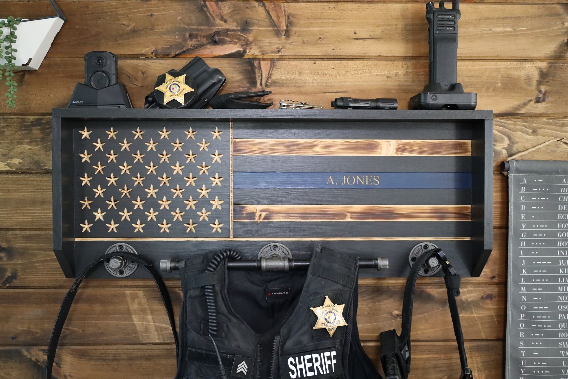 Wooden flag shelf with law enforcement gear, thin blue line, name, vest, and radio.