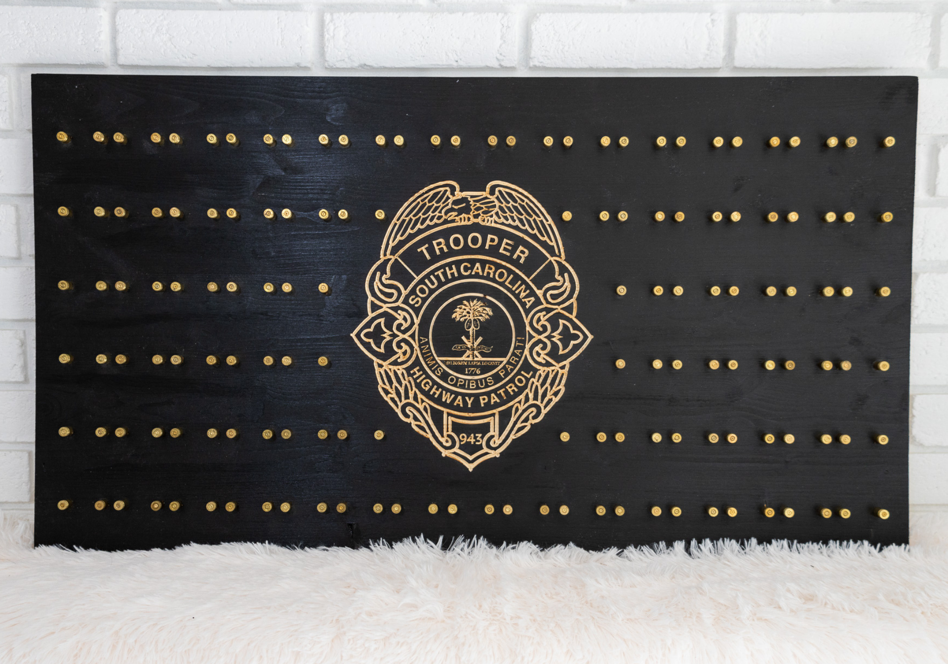 Black plaque with gold studs arranged like a flag. A gold police badge is centered.
