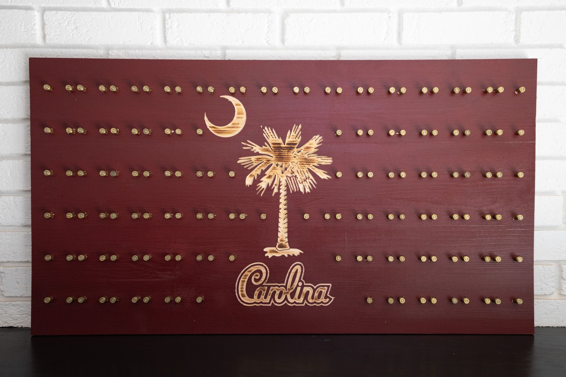 Maroon wall art with a gold palm tree, crescent moon, and rows of studs above the word “Cuba”