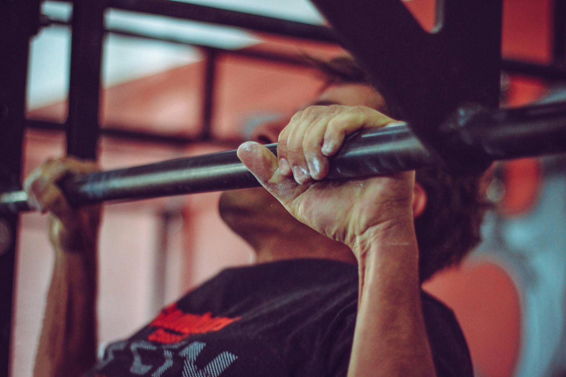 Person gripping a pull-up bar during a workout, wearing a black shirt.