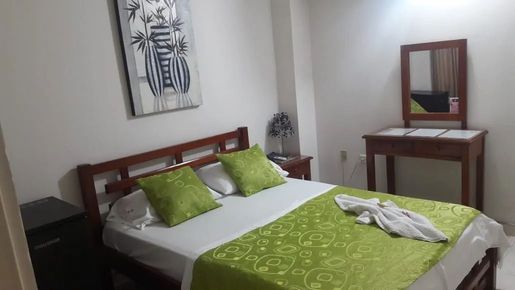 Dormitorio con cama de madera, ropa de cama y almohadas verdes