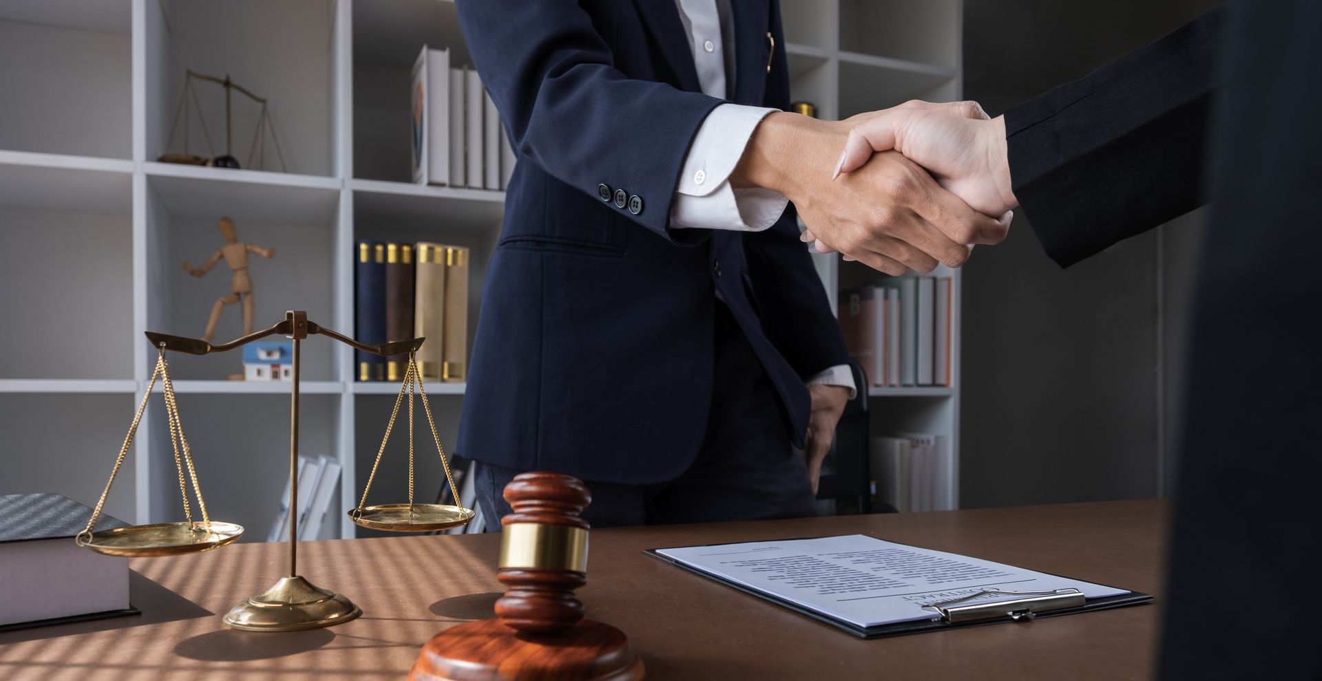 Probate lawyer shaking hands with a client beside a gavel and scales of justice