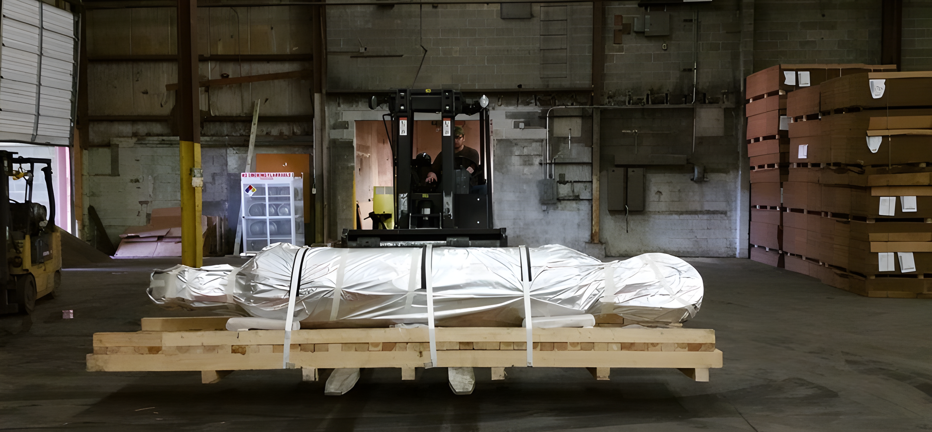 Warehouse loading dock with a pallet of wrapped goods and stacked boxes on the right