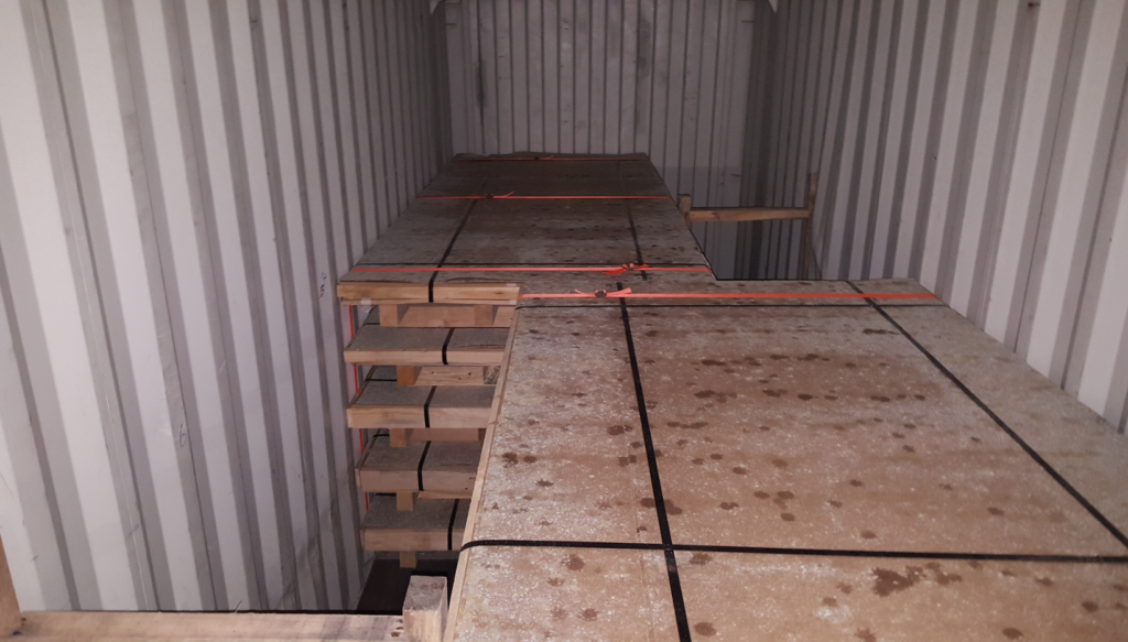 Interior of a shipping container with raised flooring and a visible gap along the left side