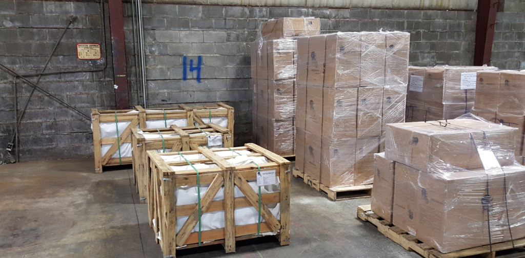 Warehouse with stacked wooden crates and shrink-wrapped pallets on a concrete floor