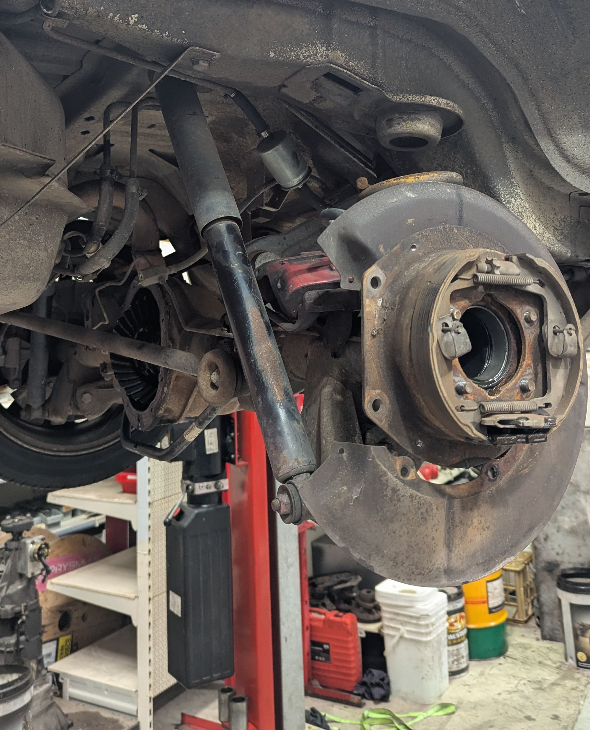 Rear car suspension being worked on in a garage. Shock absorber, brake components, and axle are visible — ATD Automotive in North Wollongong, NSW