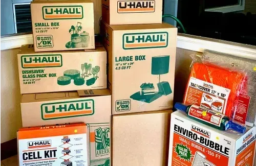A collection of U-Haul moving boxes, packing materials, and bubble wrap stacked together.