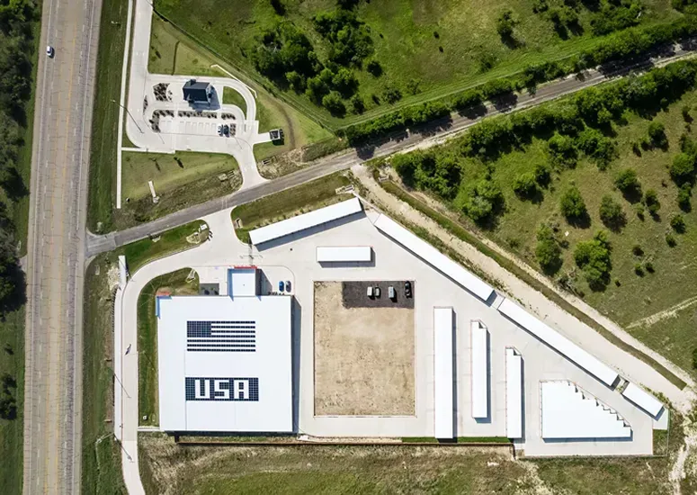 Aerial view of a self-storage facility featuring a large building with an American flag and