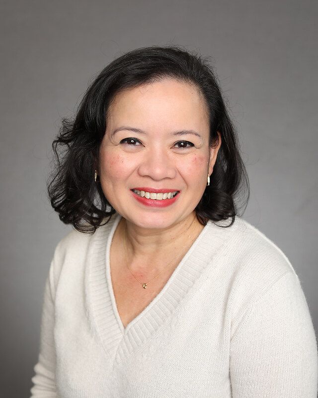 A woman in a white sweater is smiling for the camera.