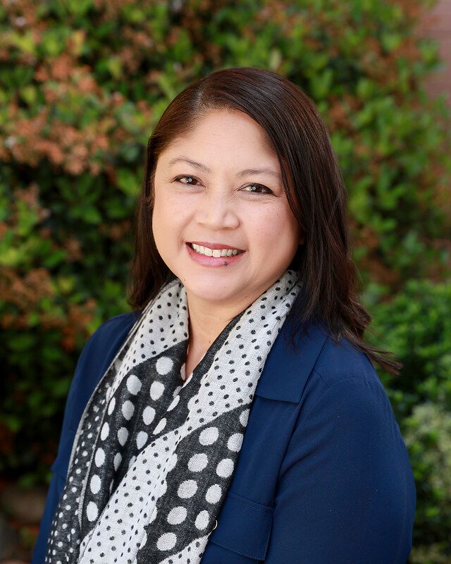 A woman wearing a striped shirt is smiling for the camera