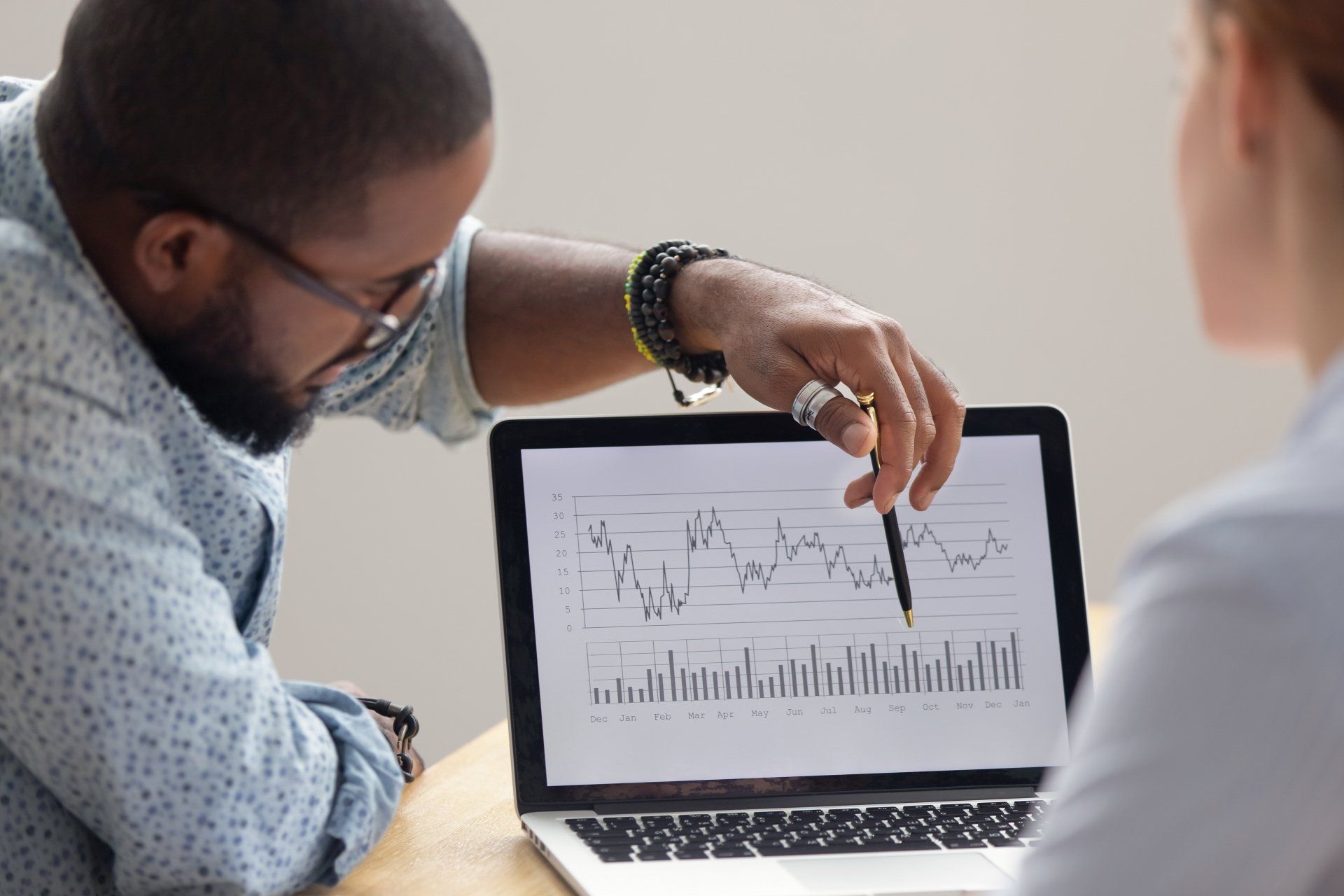Focused analyst showing client or colleague annual financial report analyzing business data on laptop