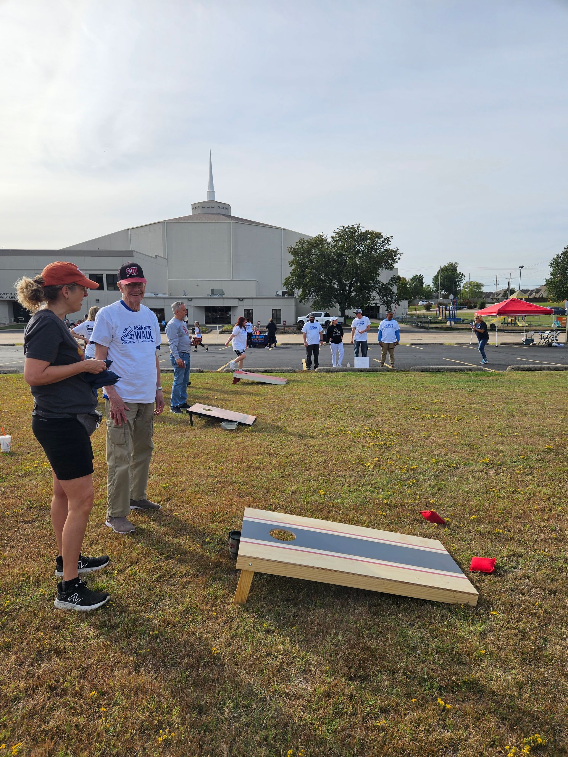 A group of people are playing a game of cornhole in a field.