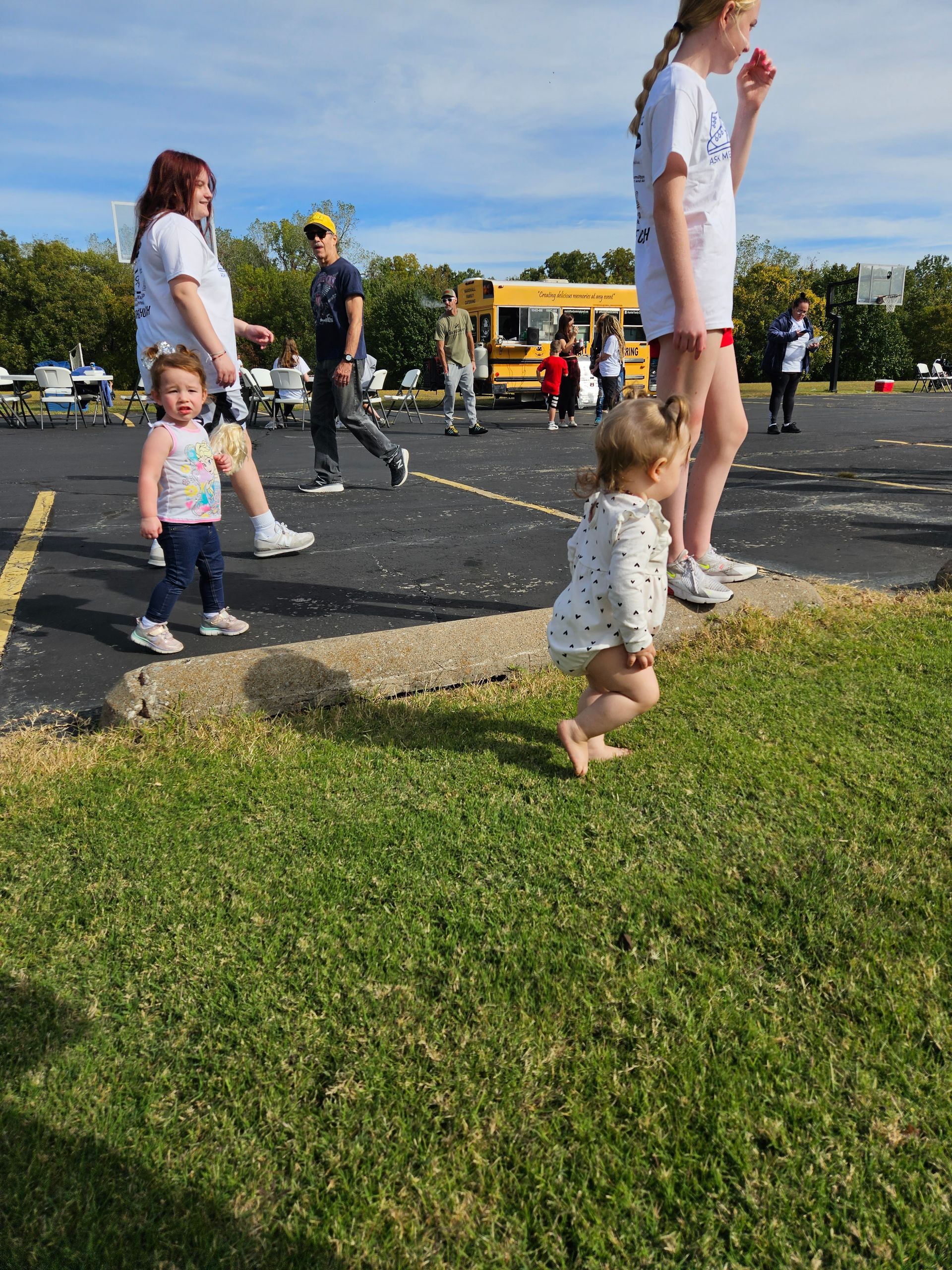 A group of children are walking in a parking lot.