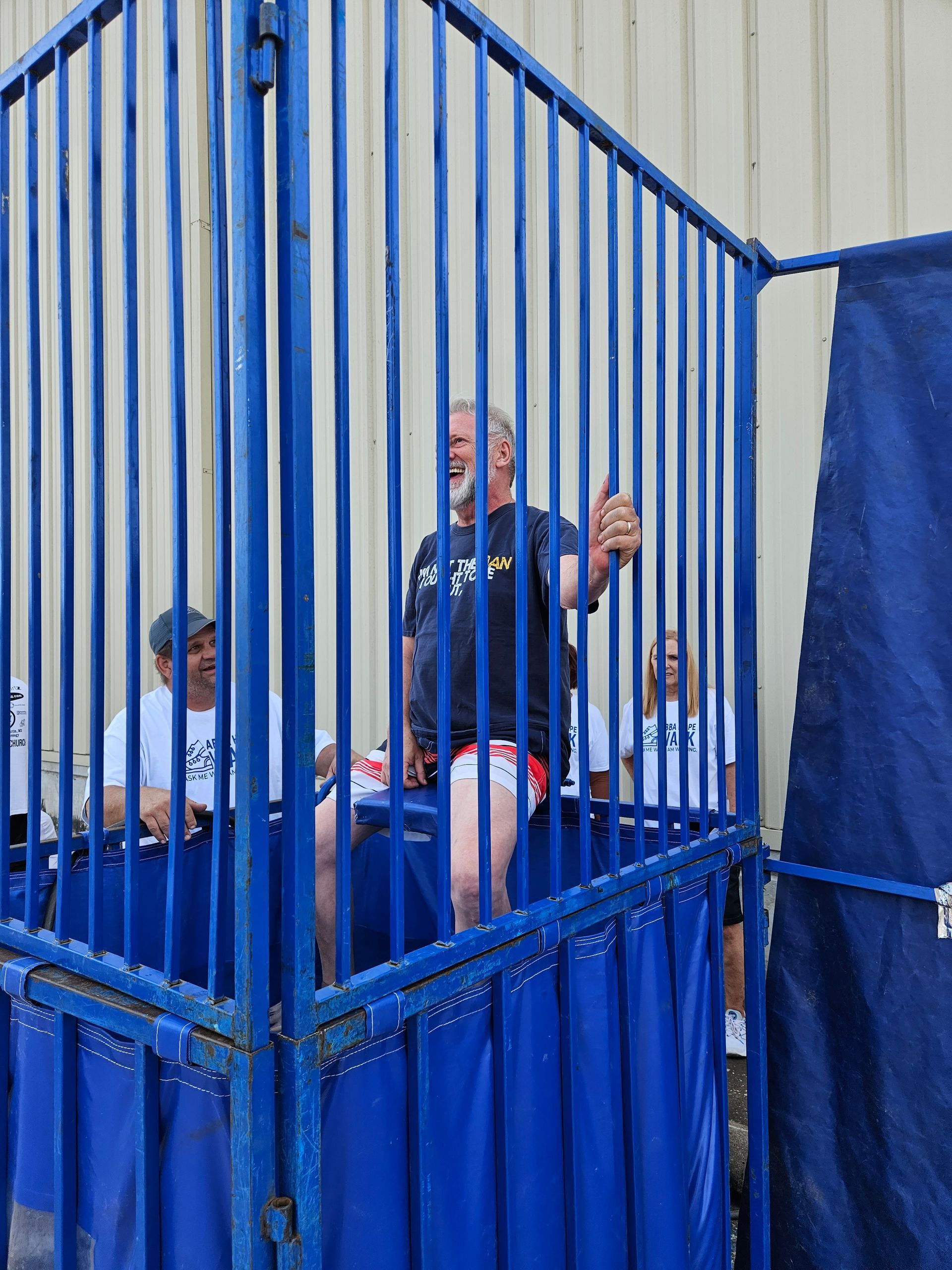 A man is standing in a blue cage with other people