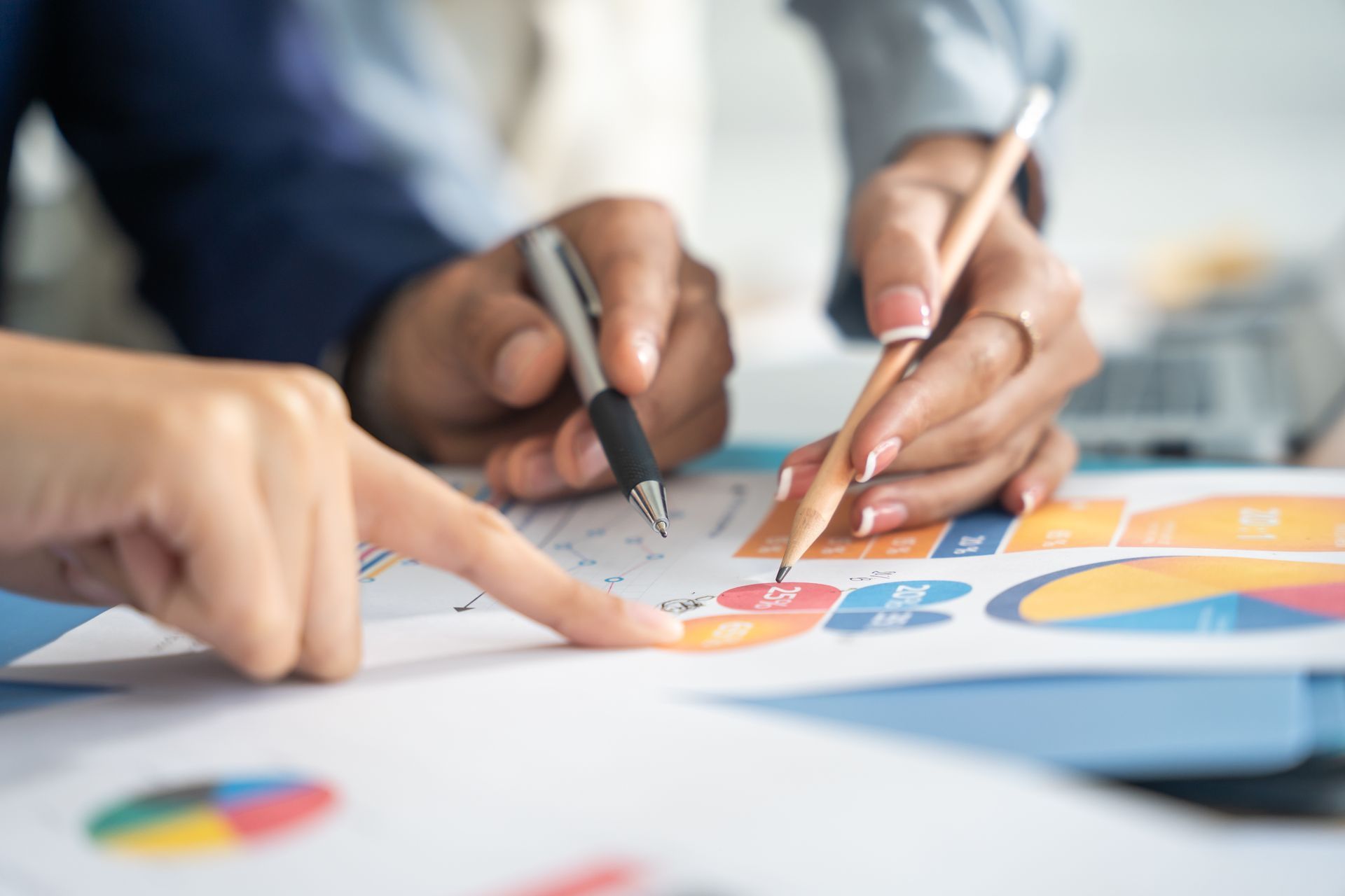 Hands pointing at a colorful chart during a team meeting