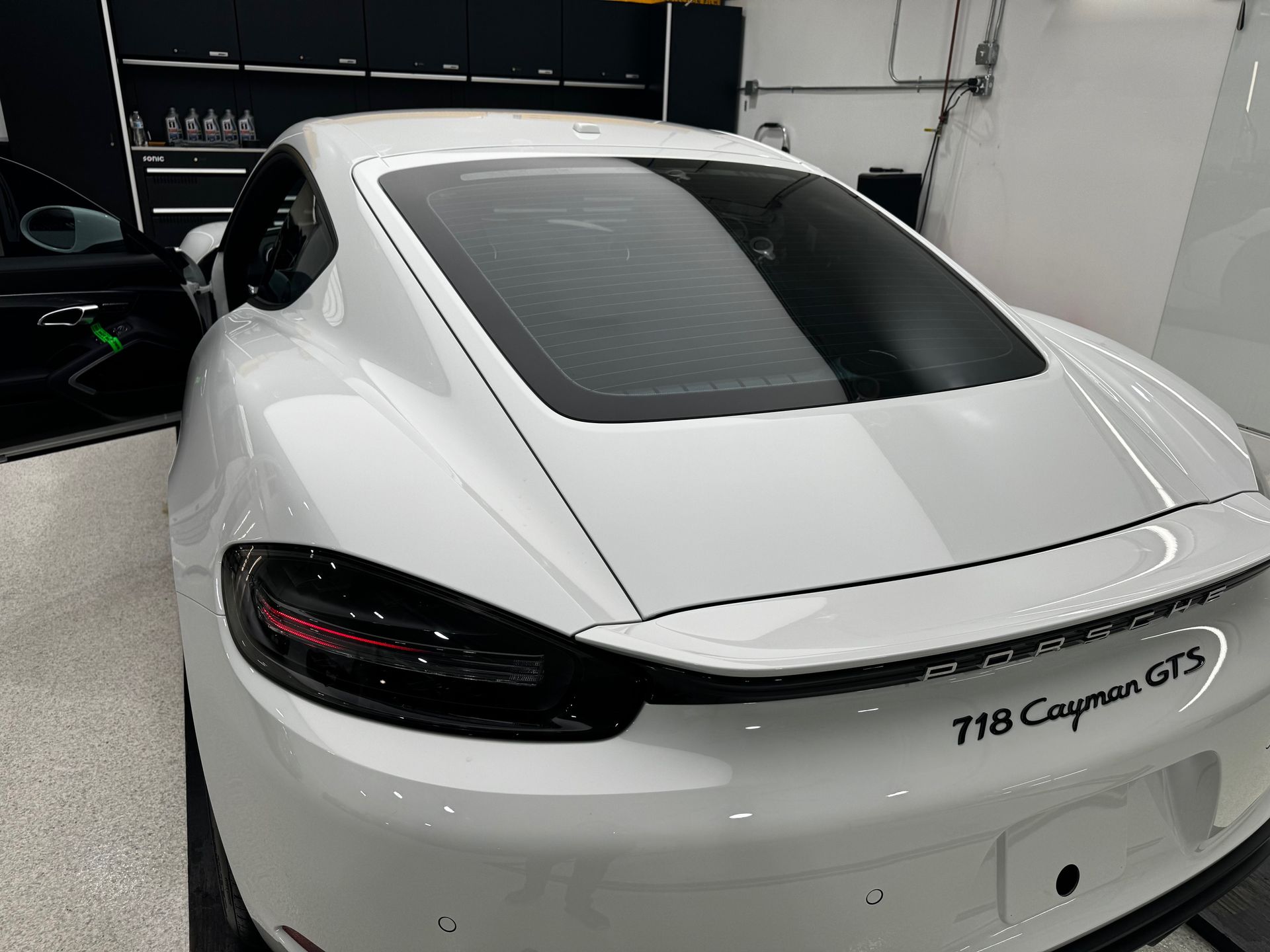 A white porsche 718 cayman gt3 is parked in a garage.
