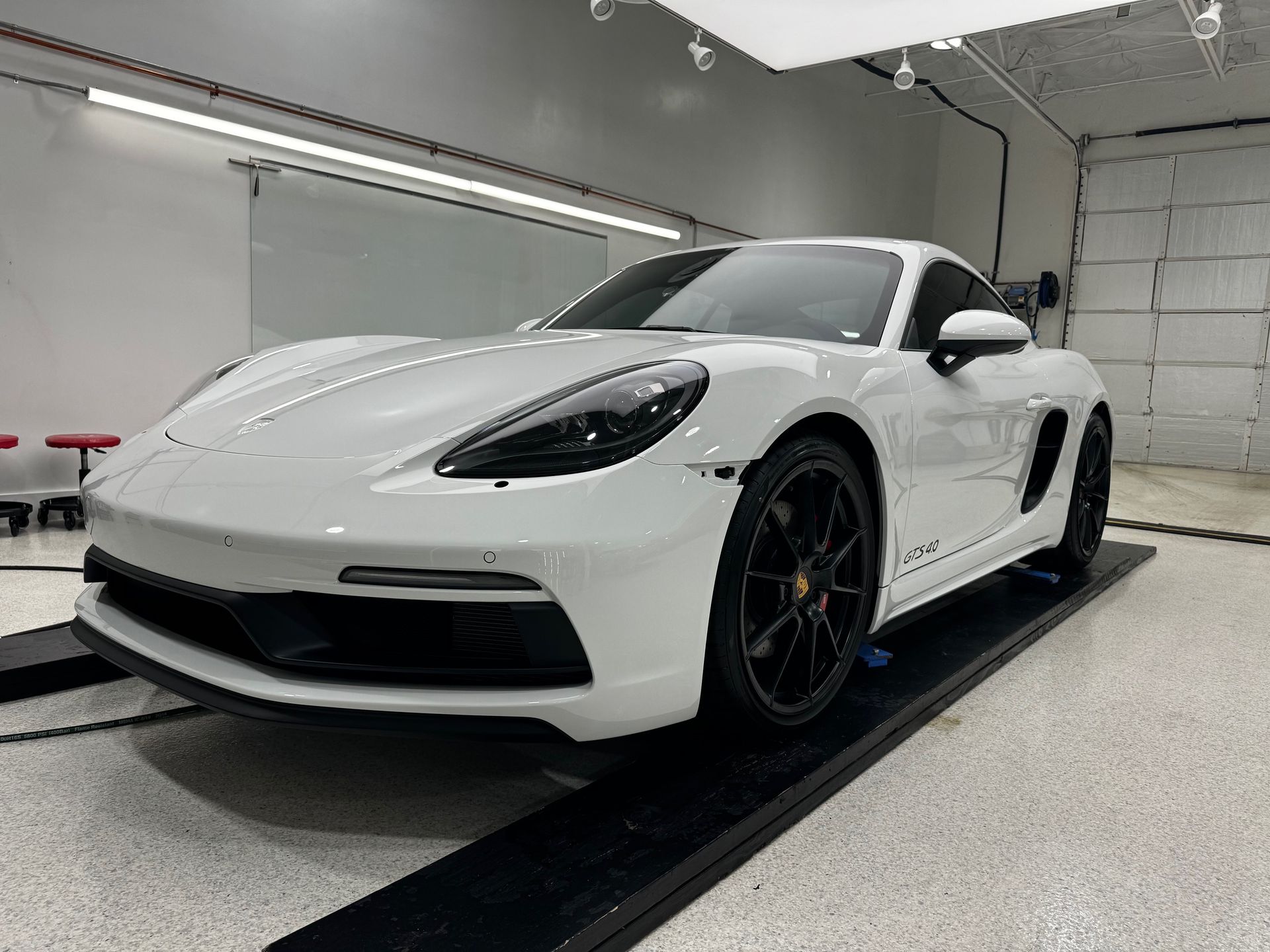 A white porsche boxster is parked in a garage.