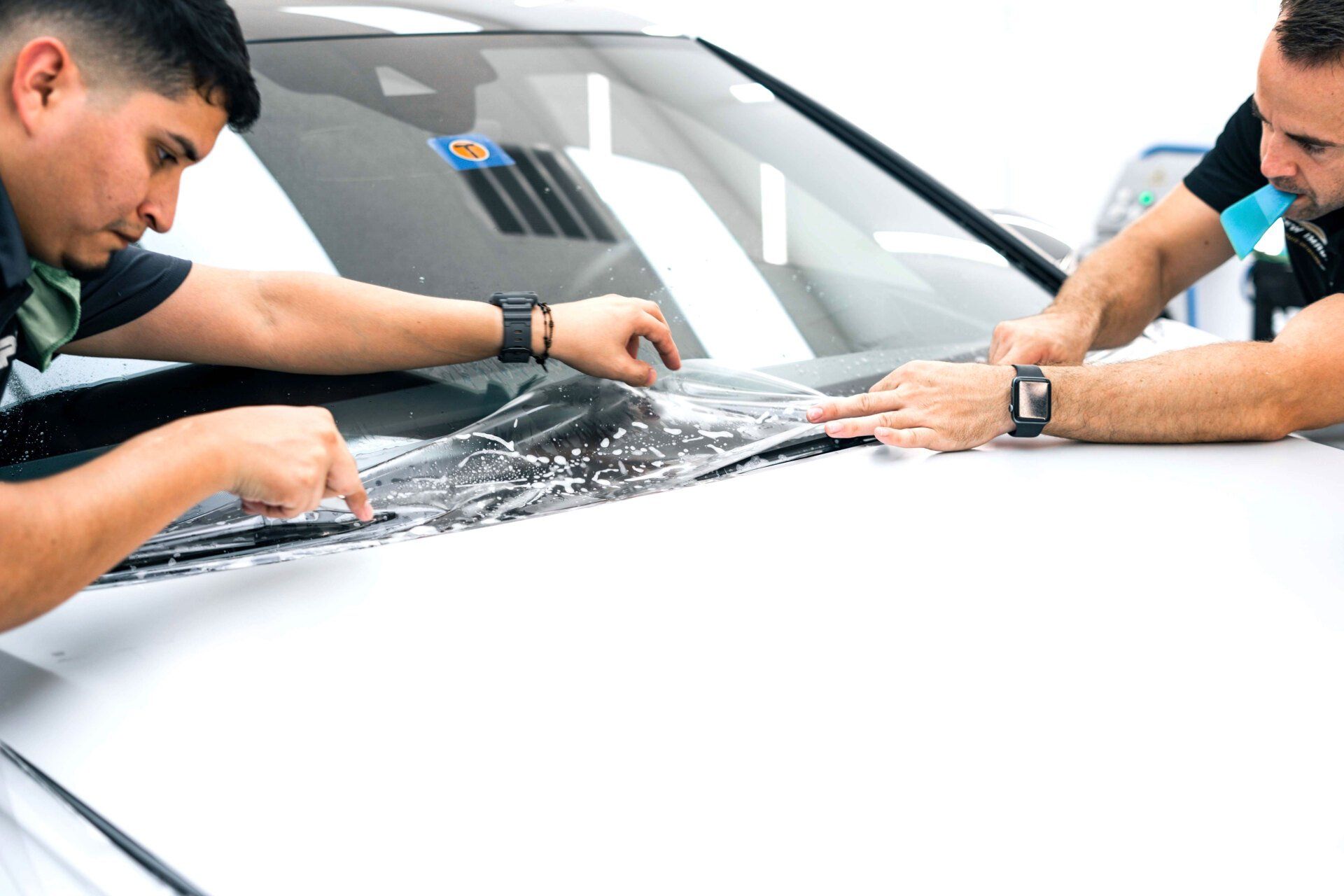 Two men are wrapping a car with a protective film.