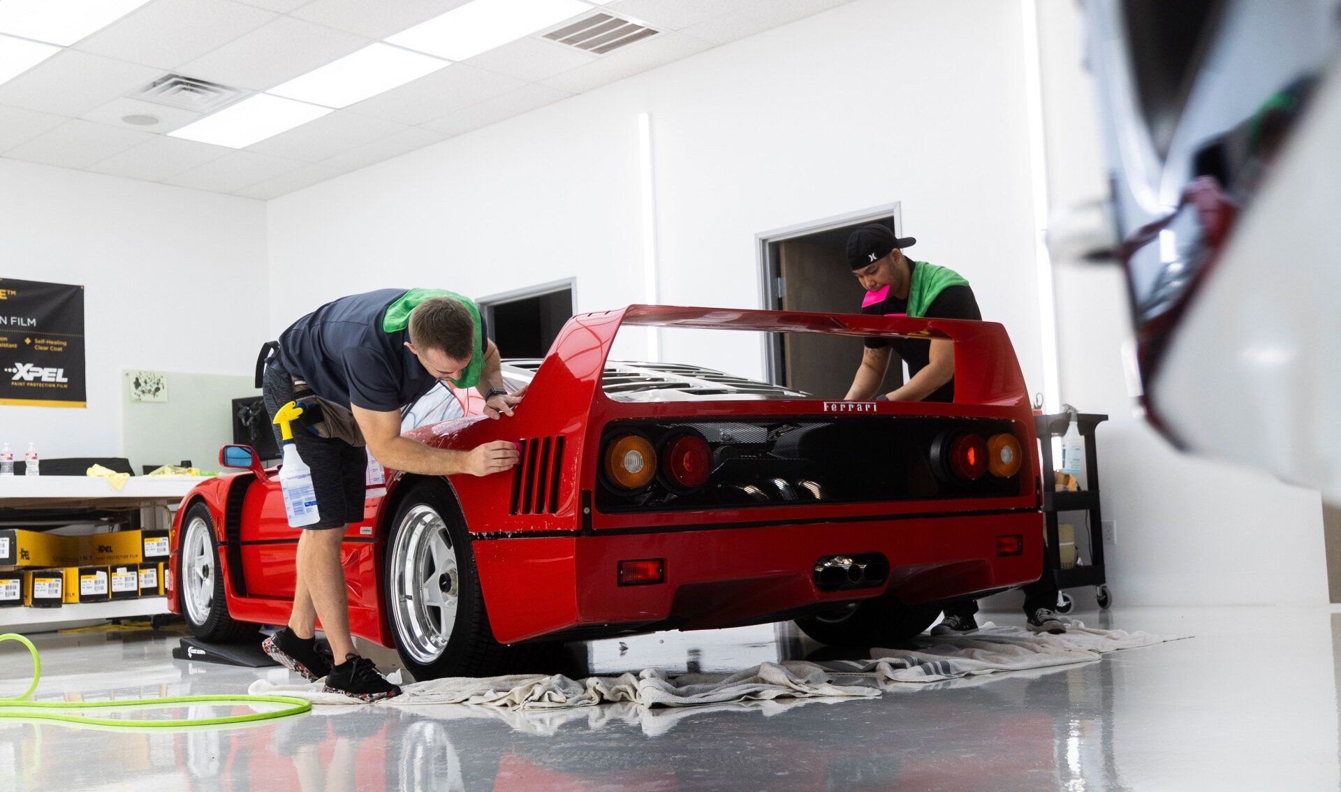 Two men are working on a red sports car in a garage.