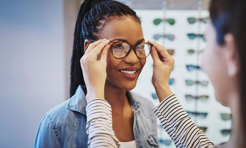 A woman is trying on glasses in an optical shop.