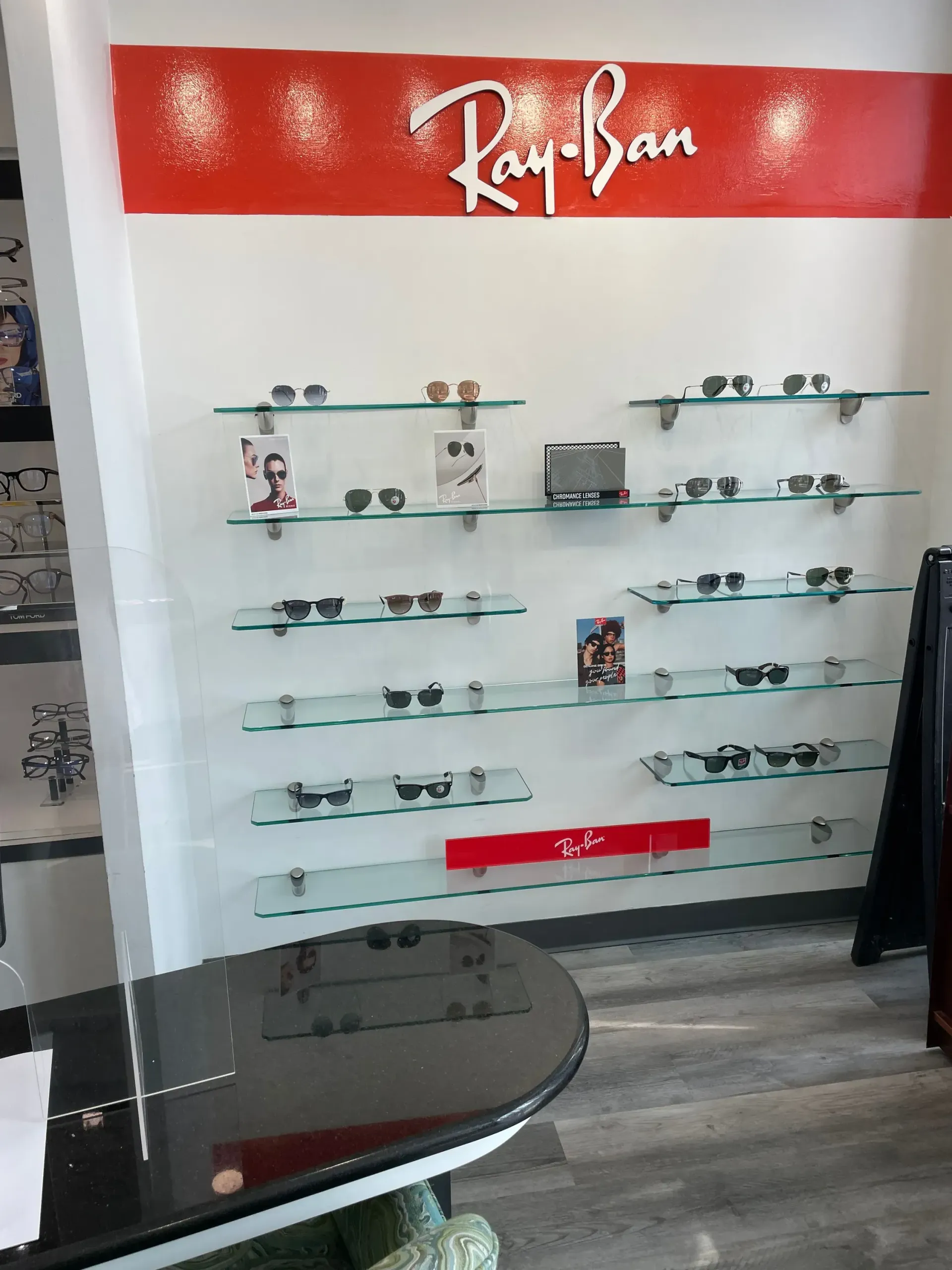Ray-ban sunglasses are displayed on shelves in an optical shop.
