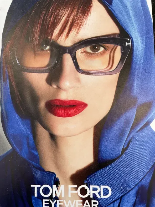 A woman wearing glasses and a blue hoodie is advertising tom ford eyewear