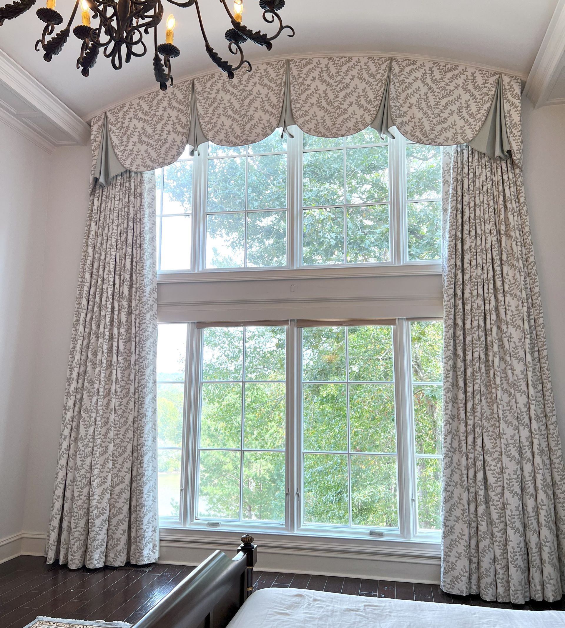 Tall window with patterned curtains in a living room, showing trees outside.