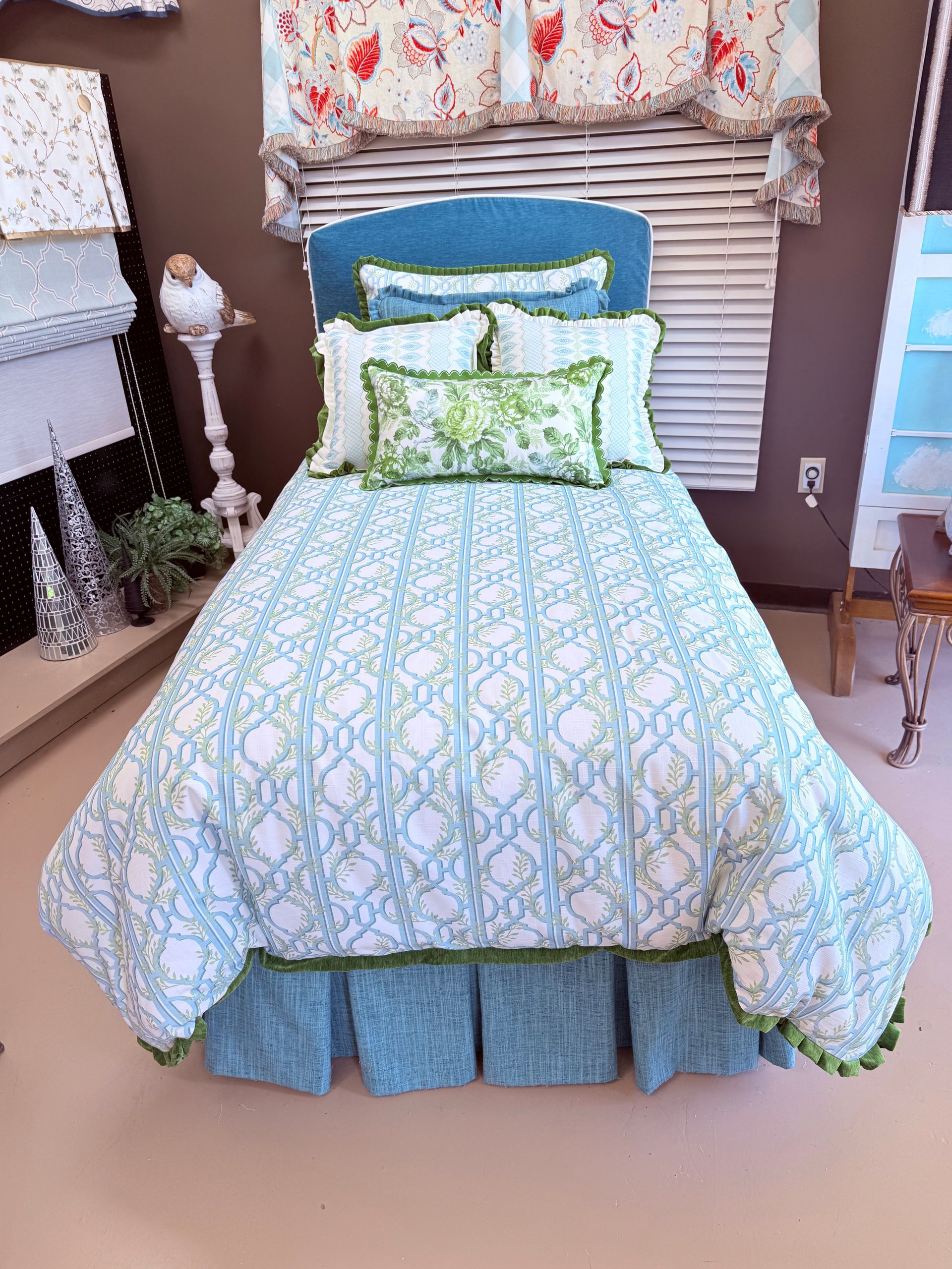 Blue-and-green patterned bed with layered pillows and a floral canopy in a cozy outdoor seating nook