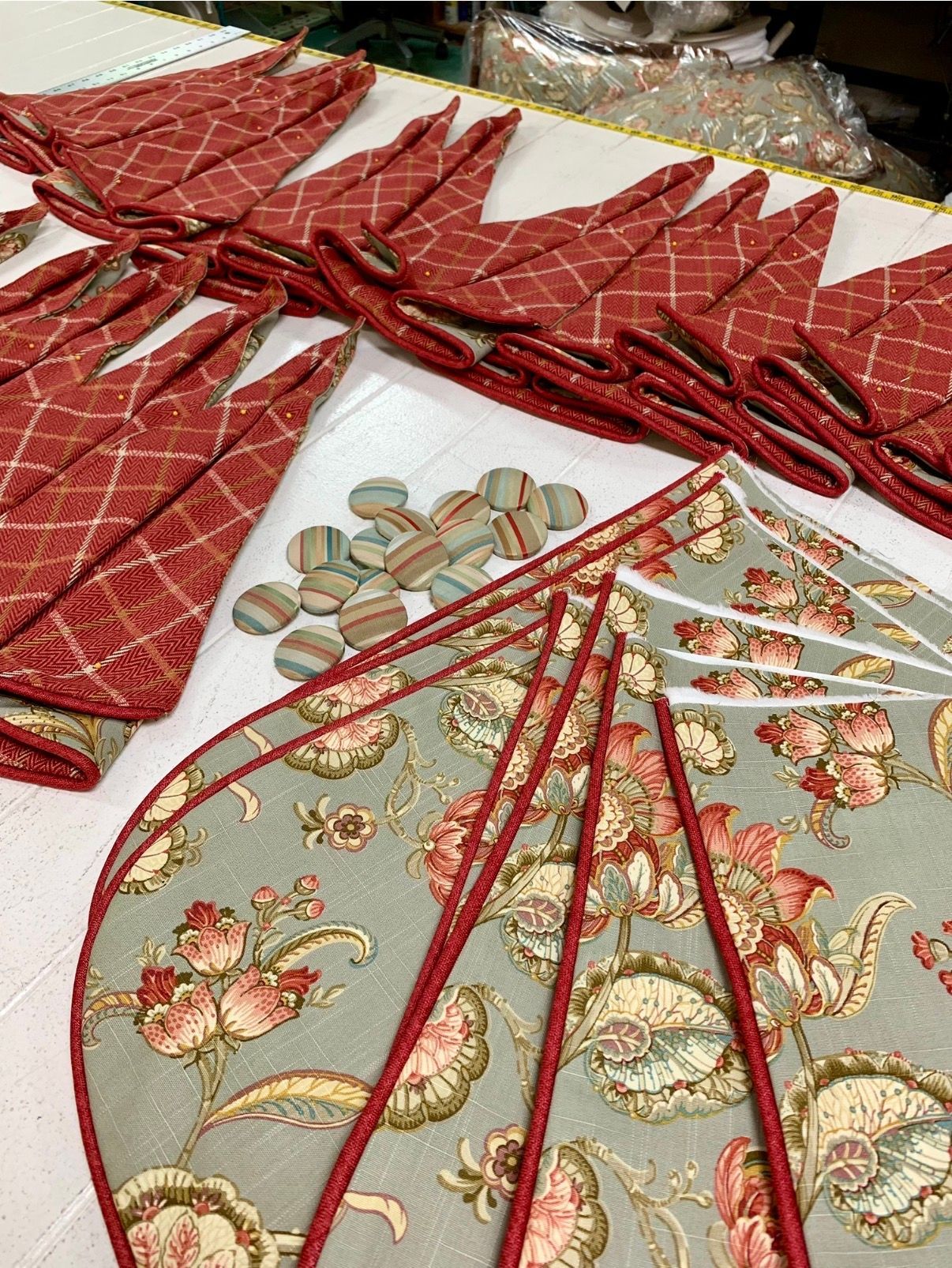 Red and gold embroidered fabric pieces arranged on a table, with floral and geometric patterns.