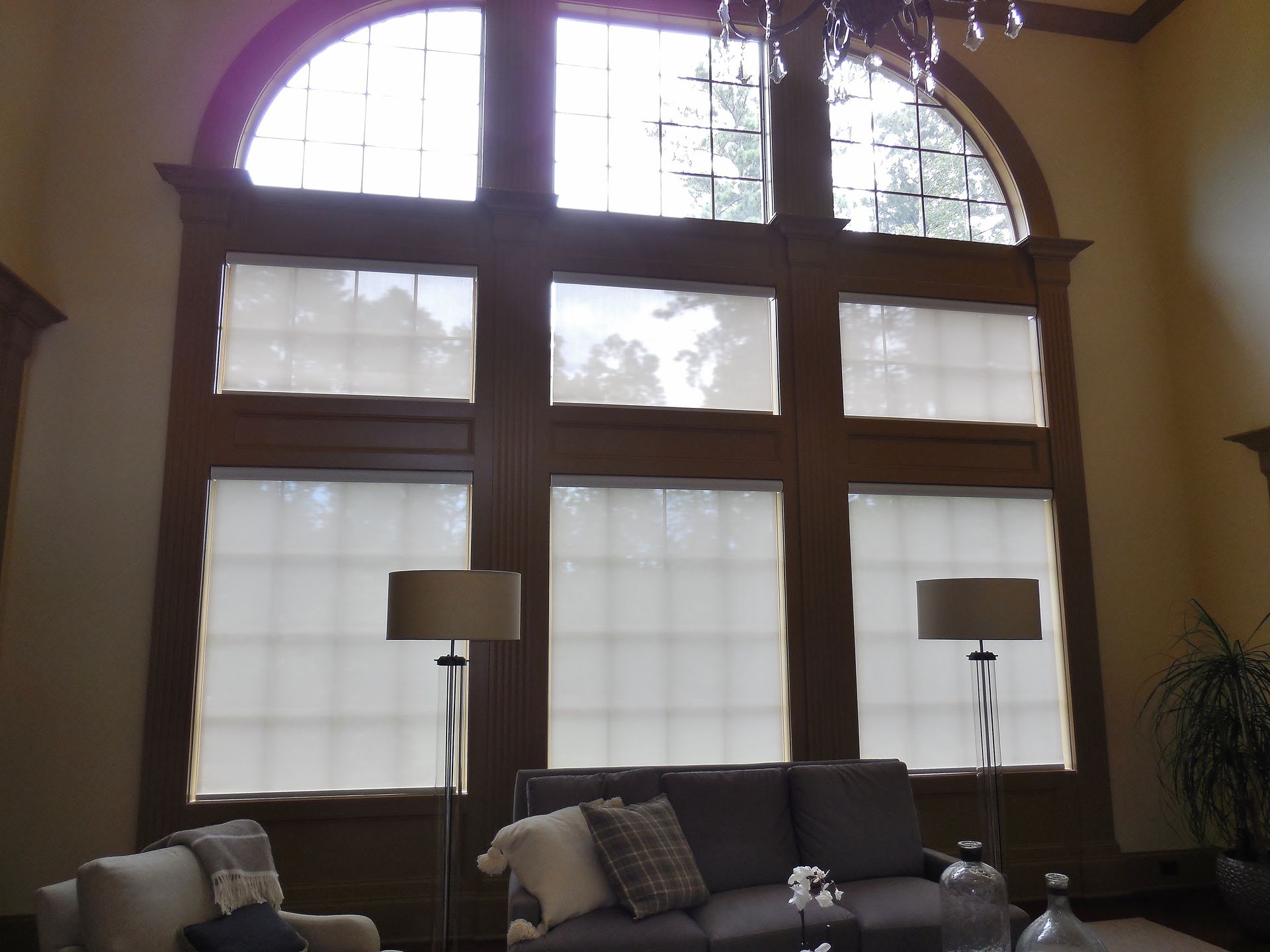 Living room with large arched windows, sofas, floor lamps, and a potted plant