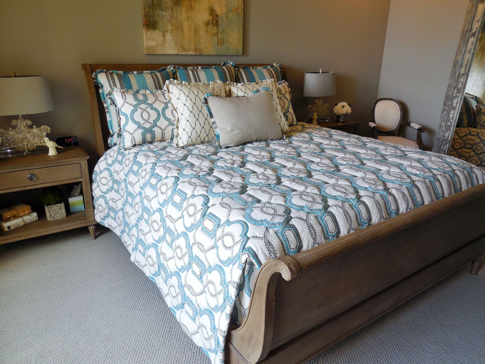 Blue patterned bed with pillows in a cozy bedroom, flanked by bedside tables and lamps.
