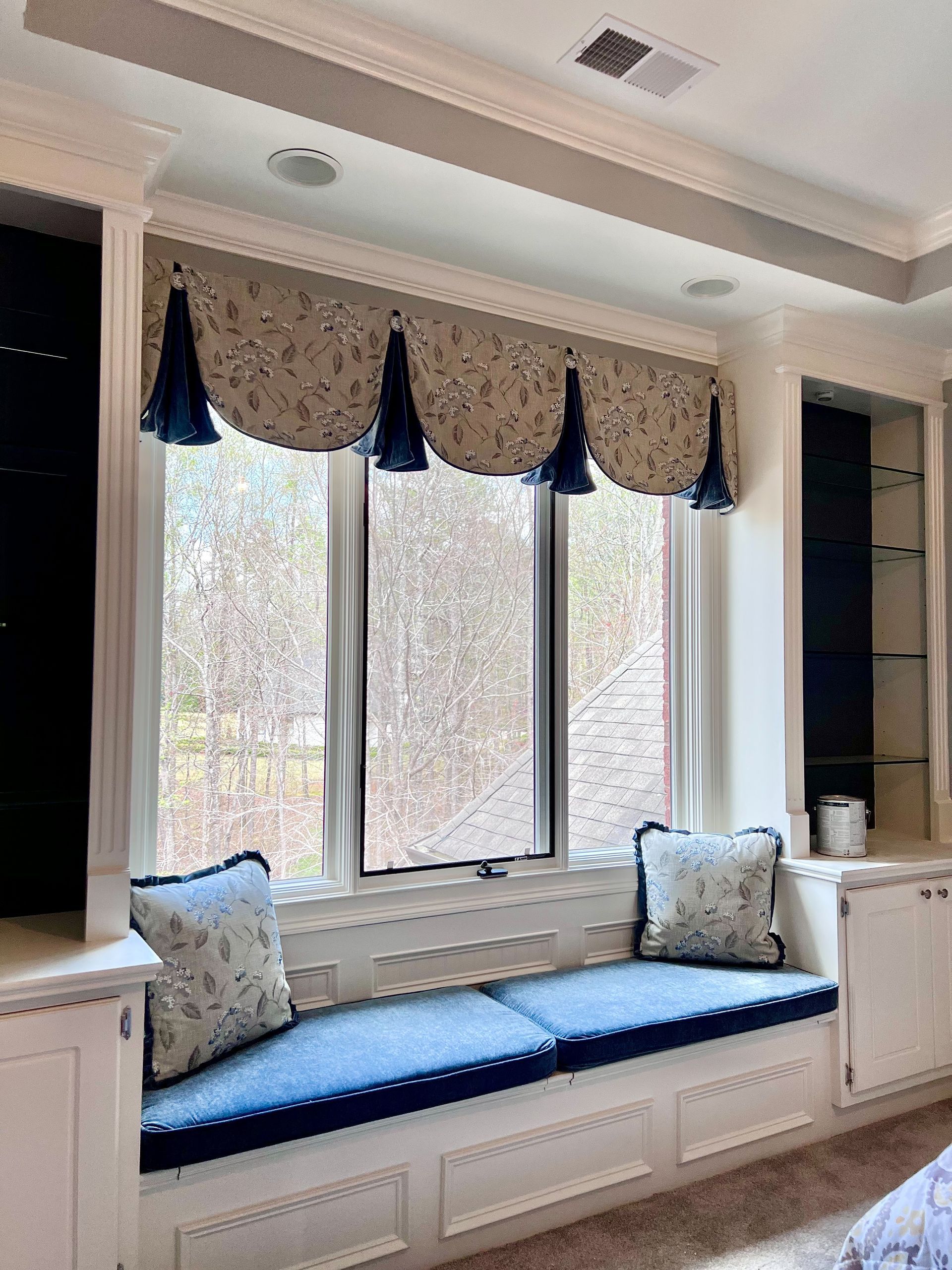 Window seat with blue cushions and patterned valance in a bright room