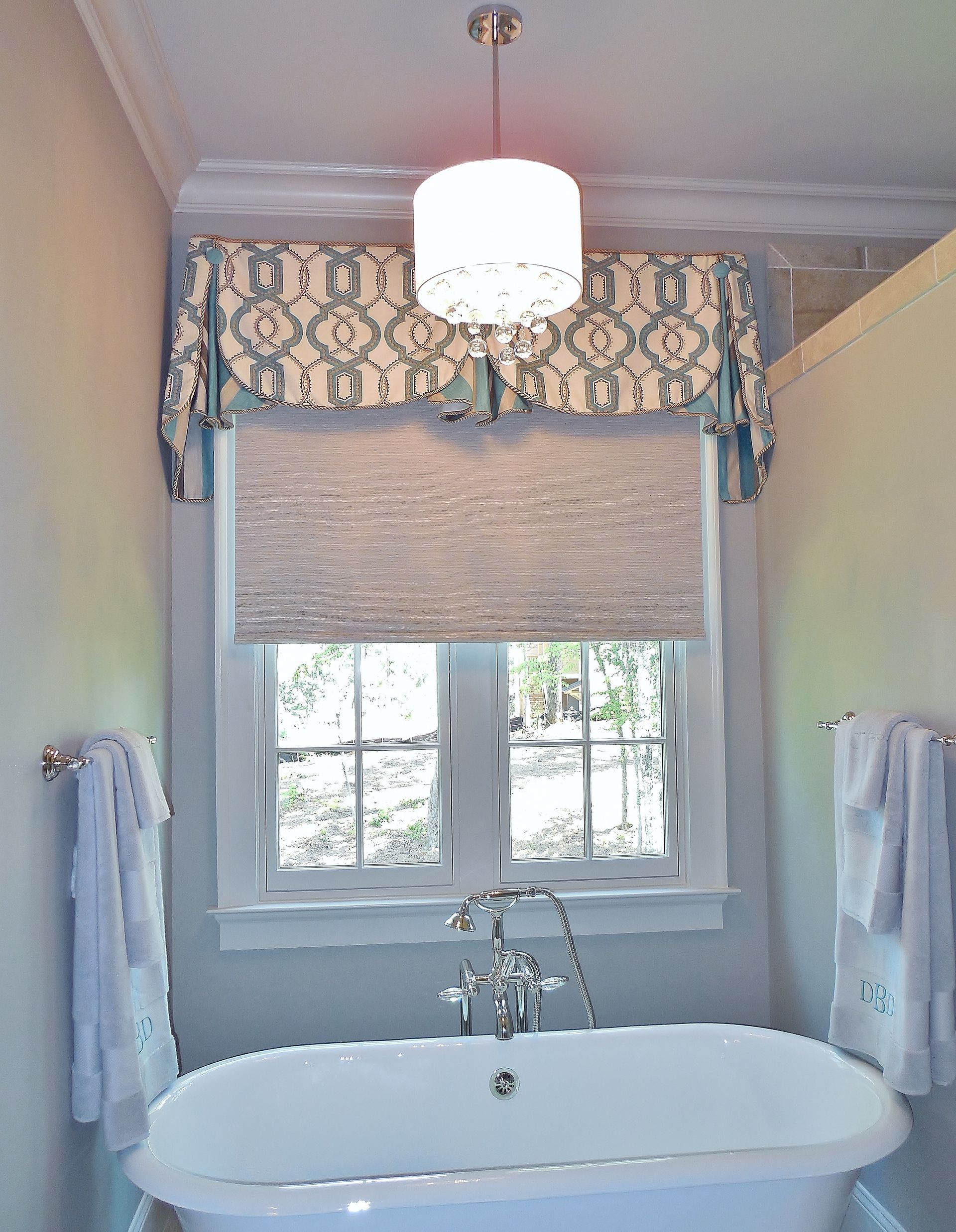 Bathroom with a clawfoot tub, window with blind, floral valance, and a pendant light overhead