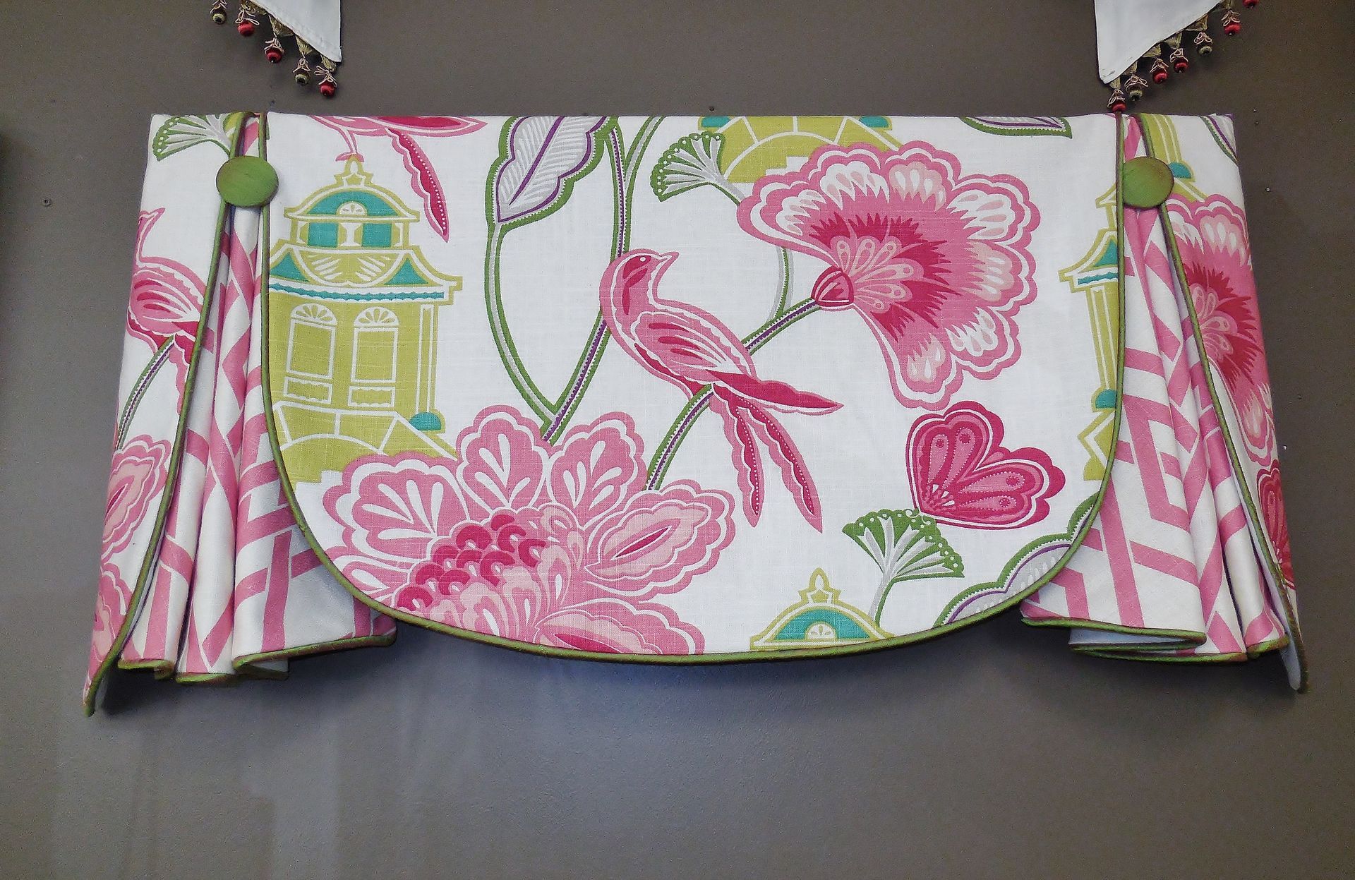 Pink and green floral clutch purse with a scalloped flap, shown closed on a dark surface.