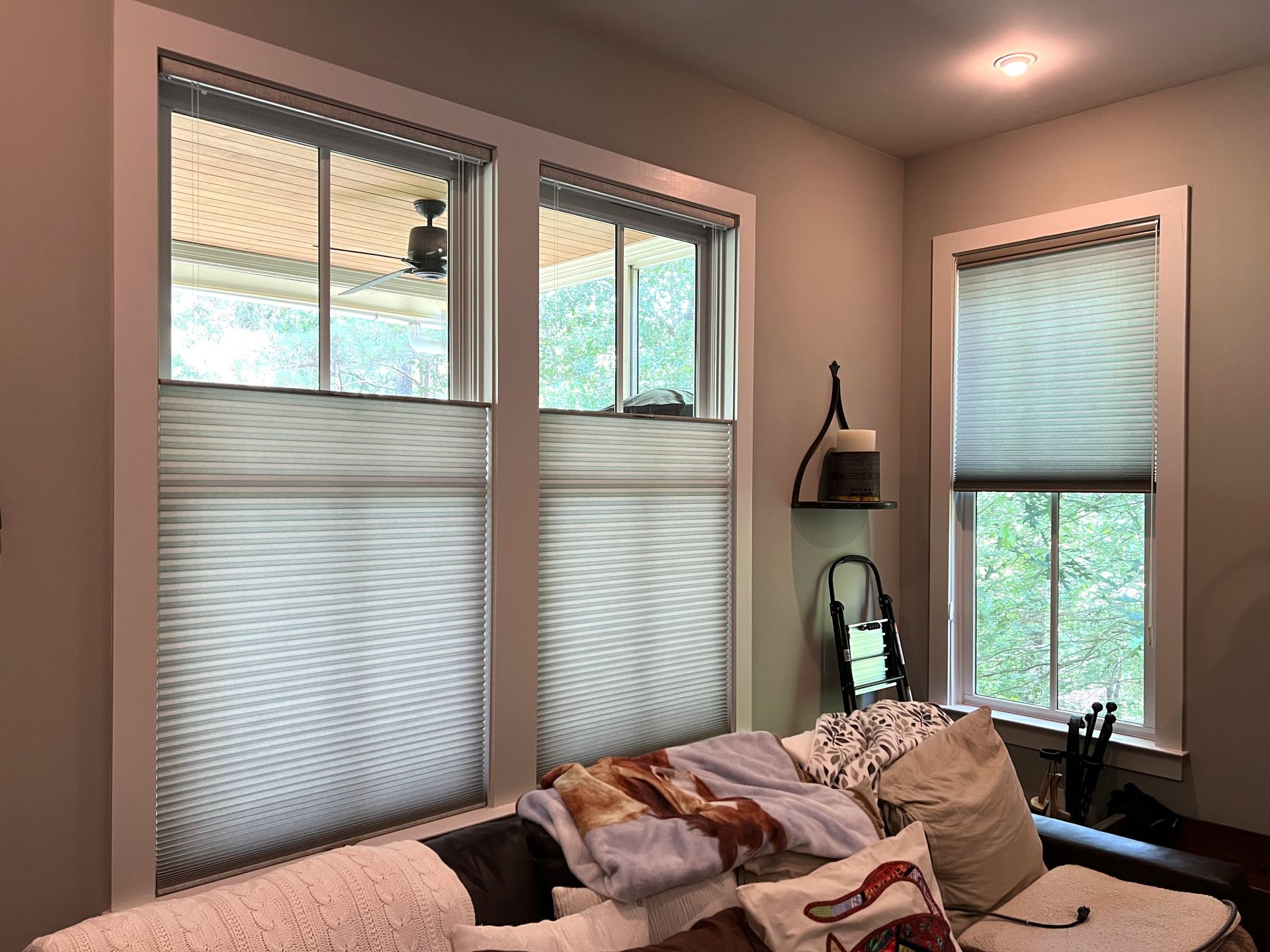 Bright bedroom with large windows, a bed, beige walls, and a small desk by the window.