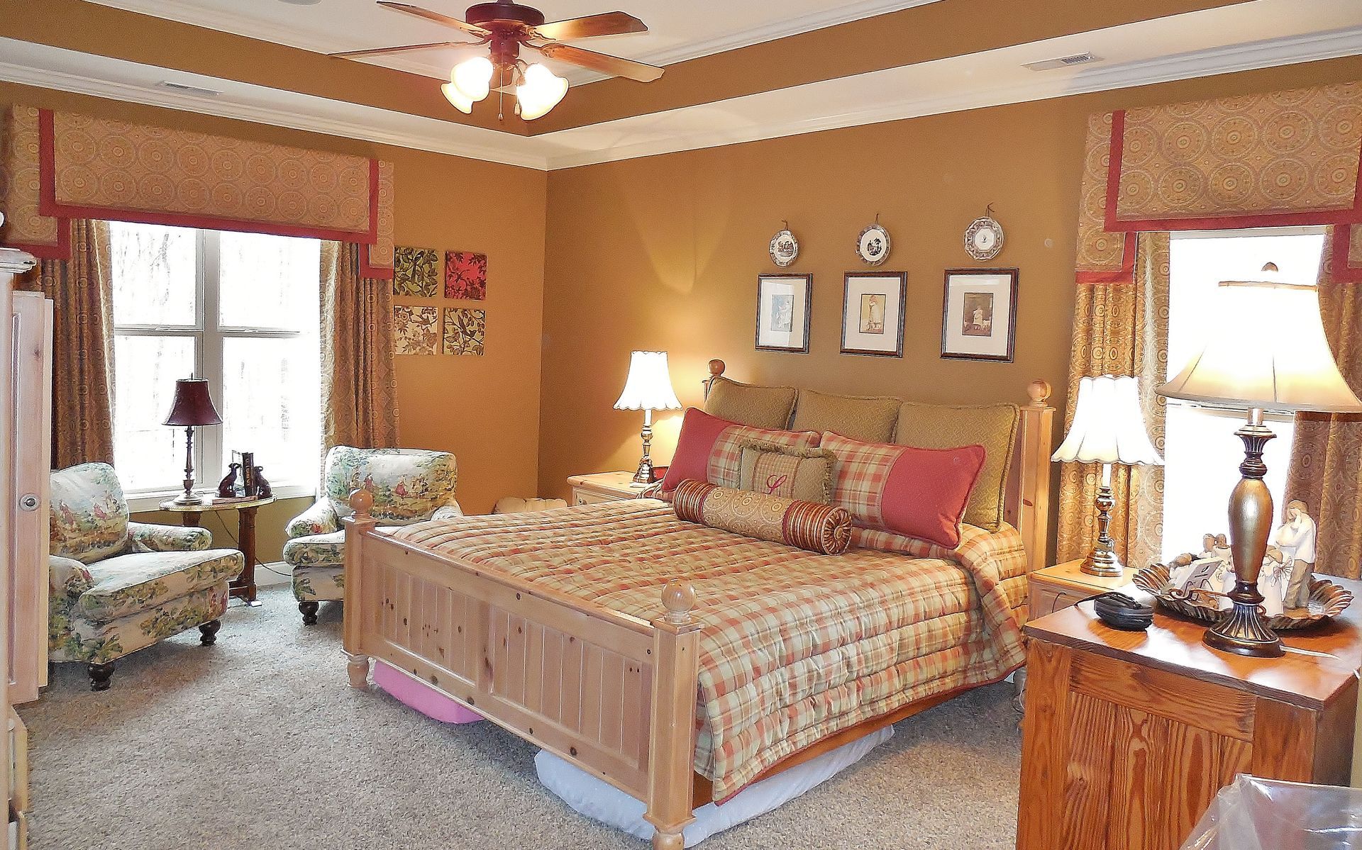 Elegant bedroom with a carved wooden bed, bedside lamps, and tan walls with framed art.
